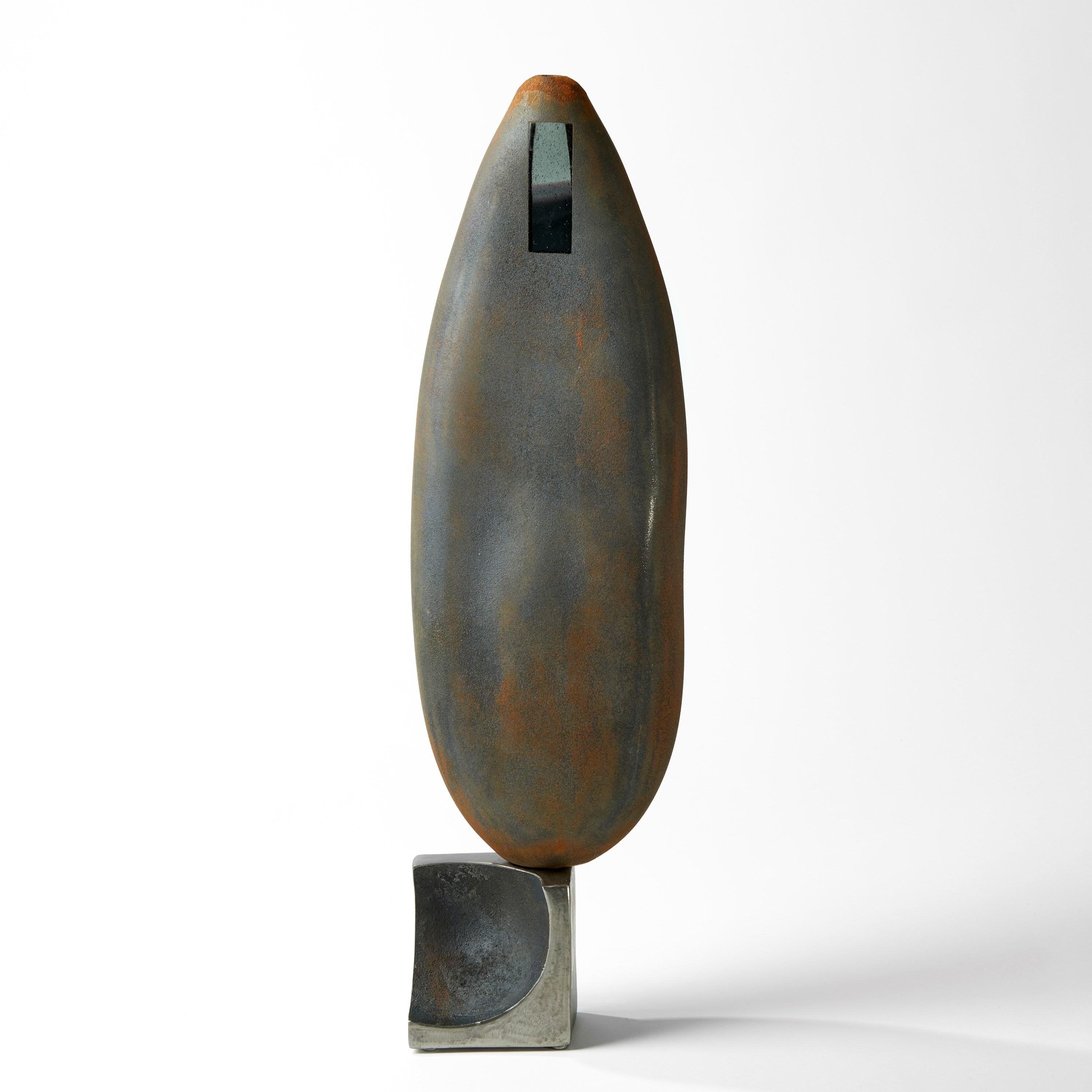 'Apertura Stone Grey 07' is a unique sculpture by the British artist, Jon Lewis, created from handblown television glass, cast iron and steel.

The top section is held in place upon the metal base below by a strong magnet.

These blown glass