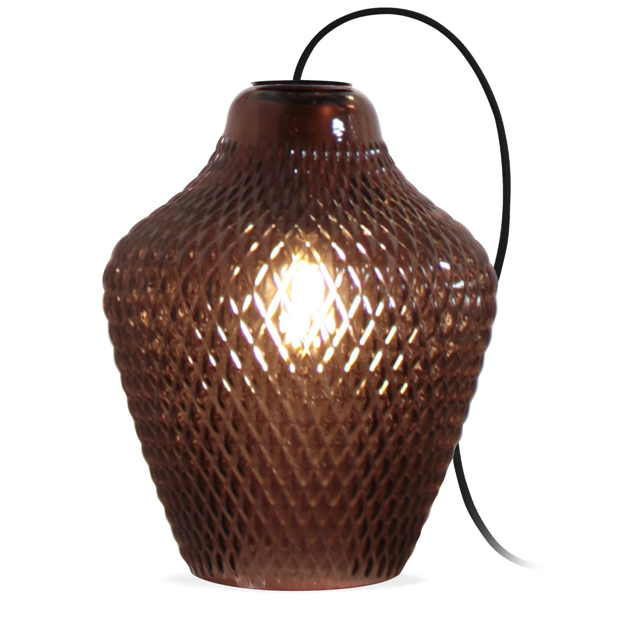 Hand blown glass table lamp with a 2m length black fabric cable.

With its atypical shape and its scale-cut surface, the Api glass fascinates both on and off to enhance any interior.
Its appearance evokes the alveoli of a beehive, the rough skin of
