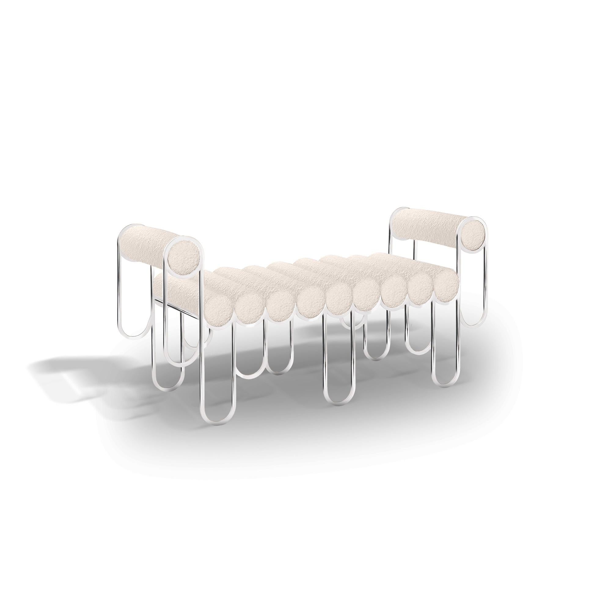 Der Sessel Apollo besteht aus einer Reihe spielerisch feiner, länglicher Metallschlaufen, die die gepolsterten Kissenrollen umarmen und so die lange, wellenförmige, schwebende Sitzfläche bilden. Die beiden Armlehnen werden von weiteren