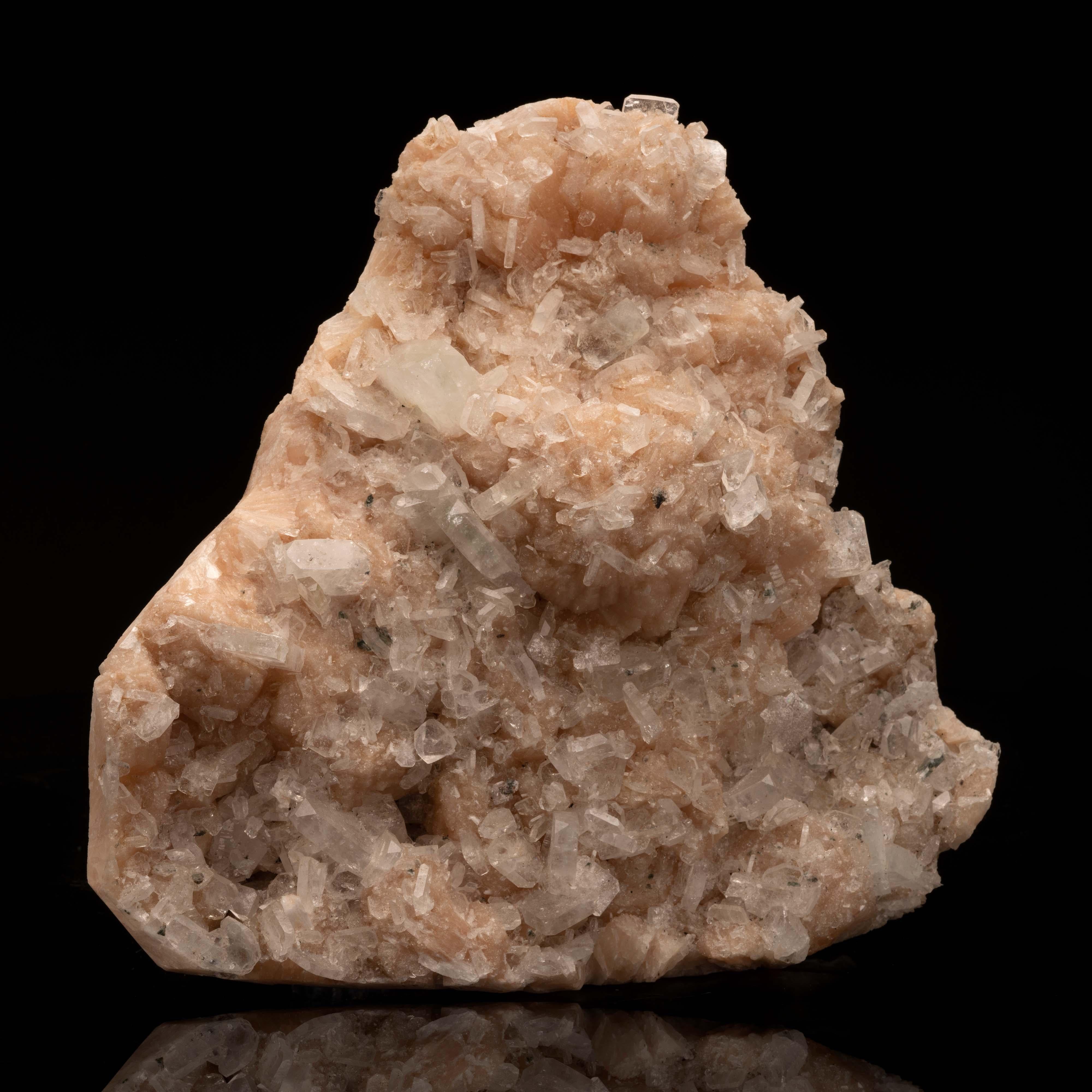 This large and textural piece features an abundance of waxy peach stilbite growing with incredibly lustrous and clear apophyllite crystals on top for a delicately-hued arrangement sure to add fascination to your cabinet or living room. The opaque