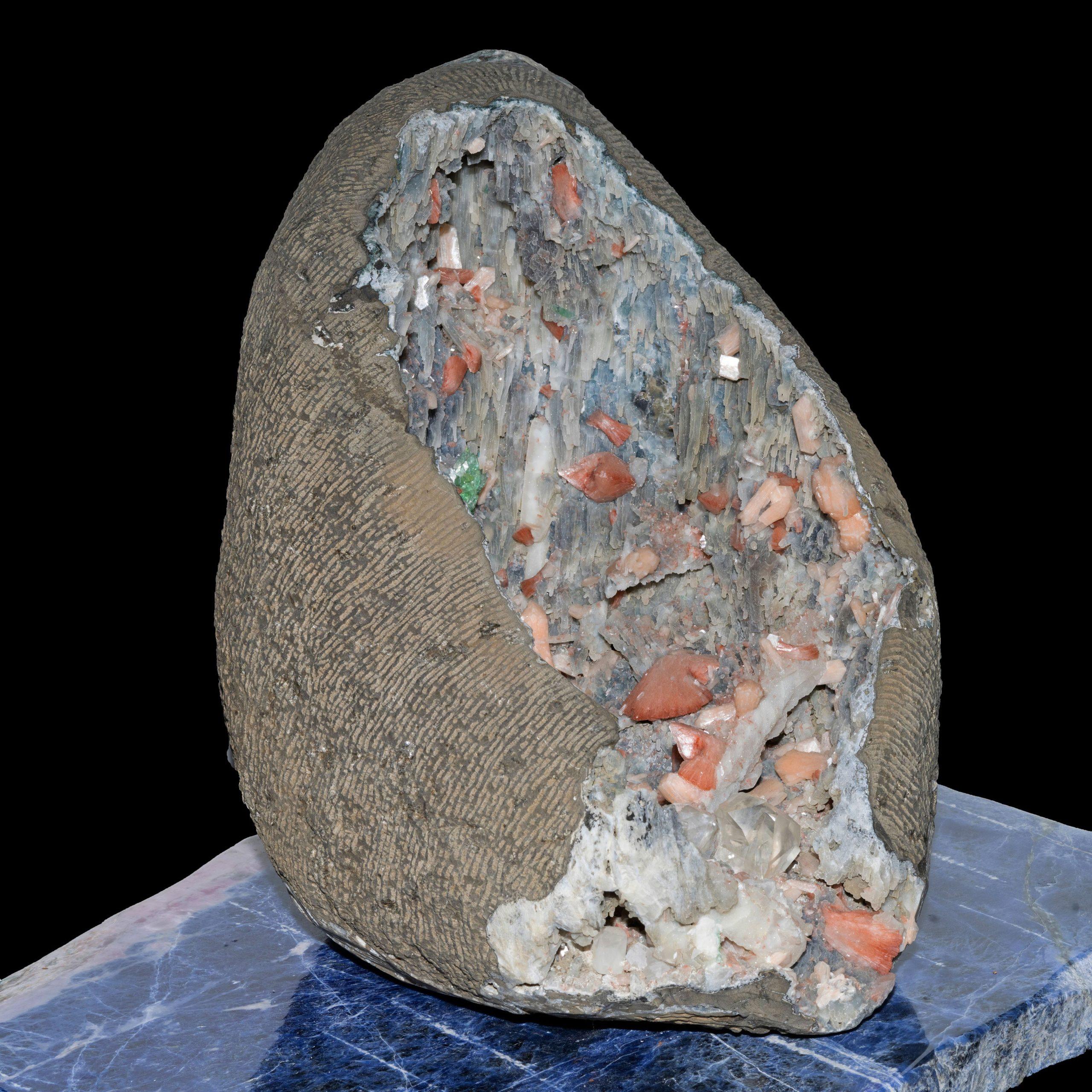 Pune, India

 This larger than life one of a kind geode boasts deposits of seven different minerals in three different classes, with stalactites of grey-blue chalcedony covered with a shimmering druzy quartz. This piece features three large
