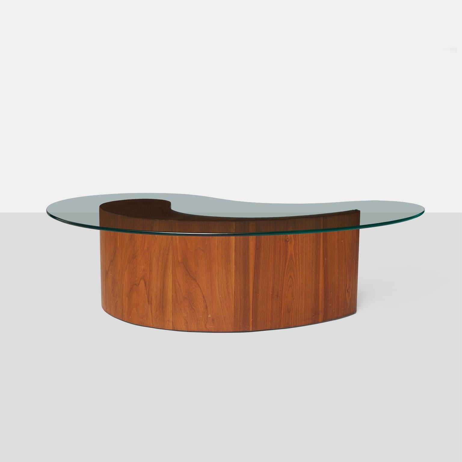 A coffee table with walnut base shaped like an apostrophe and a 1’2? glass top, attributed to Vladimir Kagan.