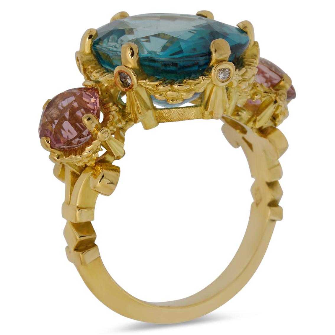 Intricately handcrafted in 18kt yellow gold this exquisite ring features a breathtaking sky blue oval cut zircon aloft a signature William Llewellyn Griffiths garland setting studded with six round brilliant cut white diamonds. Measuring 16mm long x