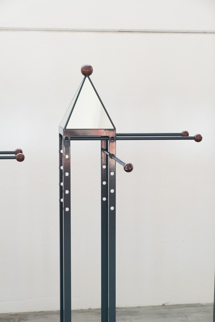 Wood and brass coat rack, set of 4, 1970s
Cherry wood base, iron columns painted mouse gray and 	brass ball feet. Top pyramid with mirror. Each with 4 arms 	iron movable and adjustable in the 5 holes present at different heights on the columns.