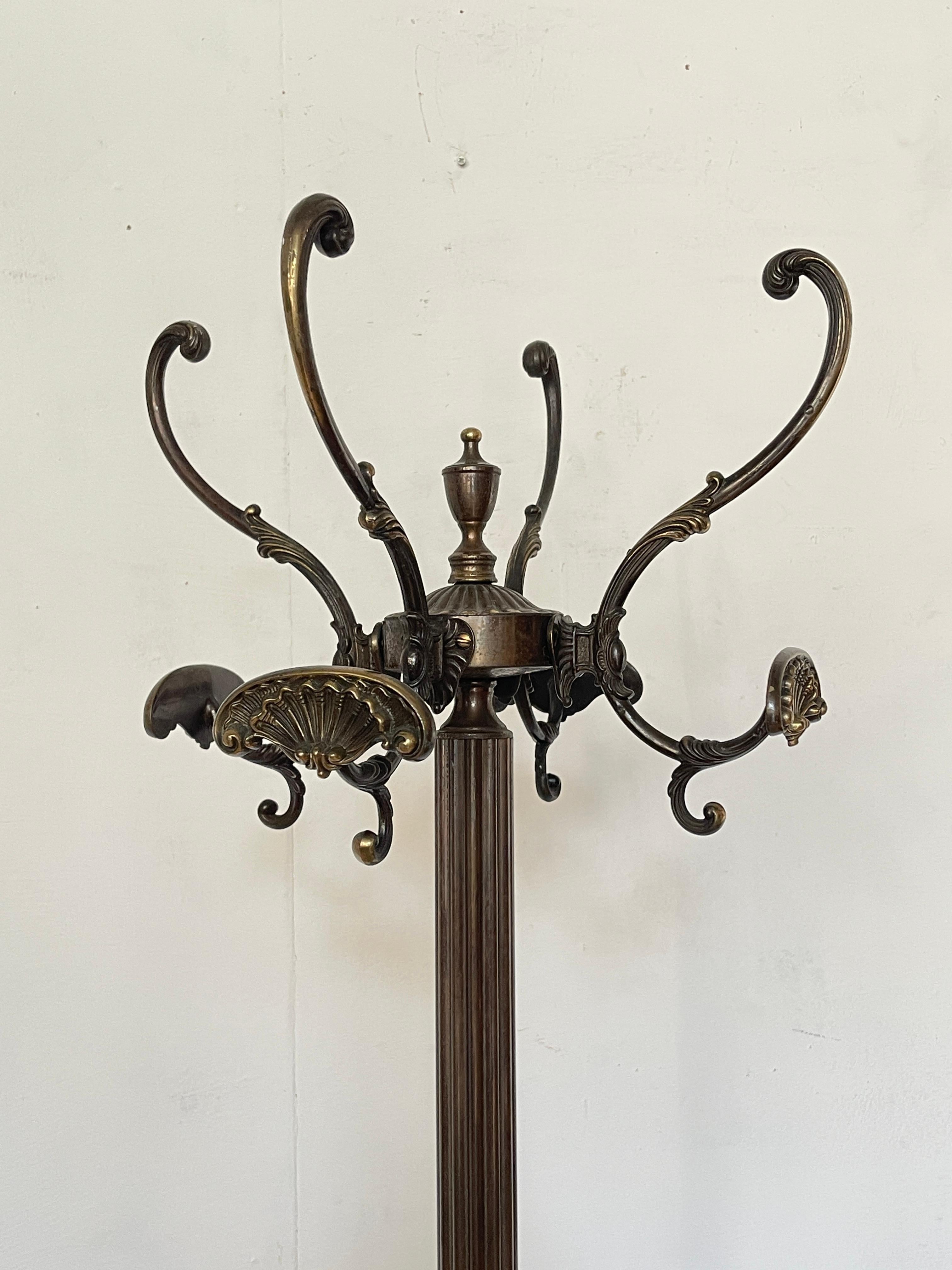 Forged bronze coat rack is a marvel of design and craftsmanship, combining elegance and functionality. The bronze frame, with its curved and delicately carved details, creates a refined visual effect, while the central column and sturdy arms provide