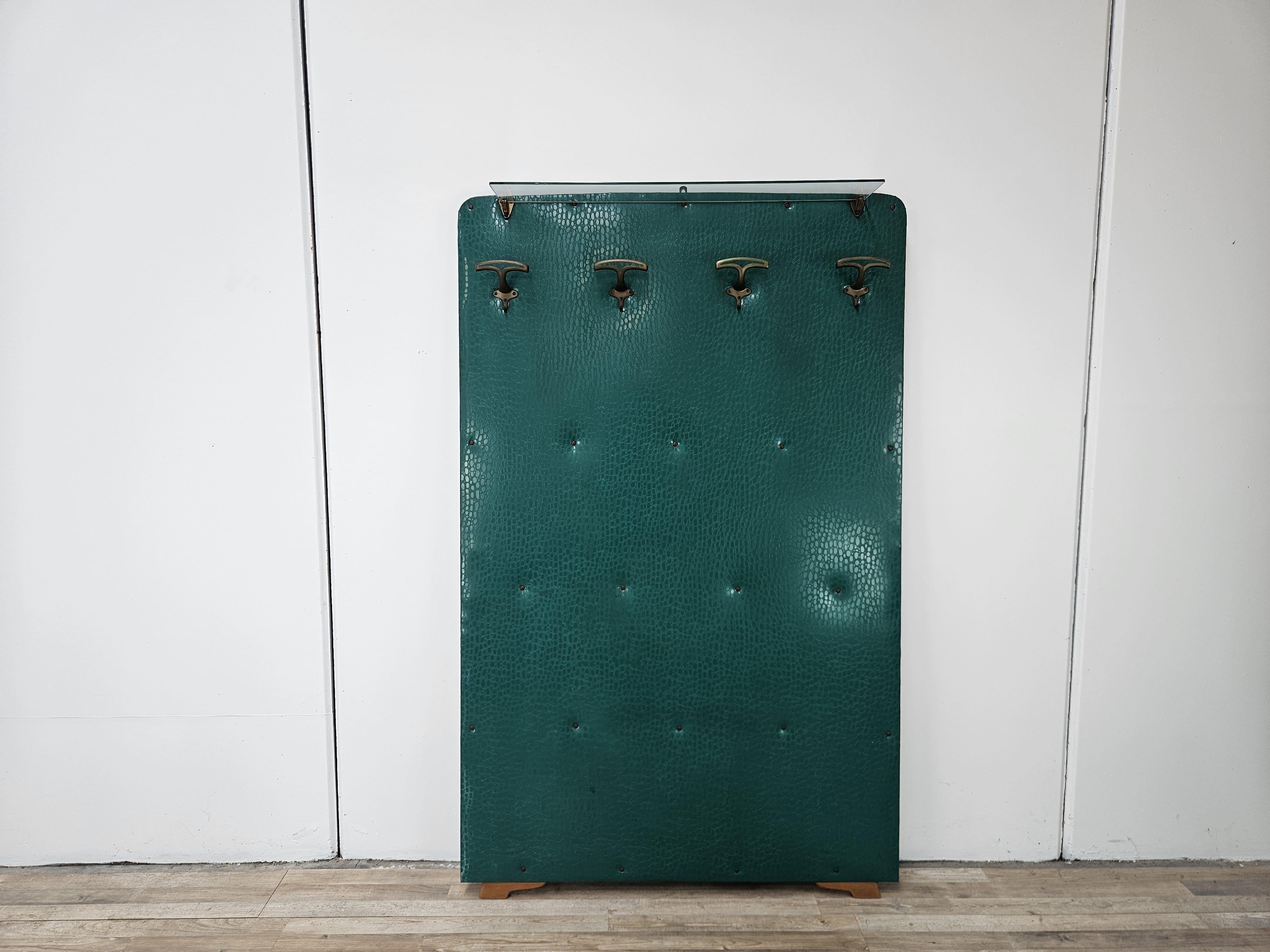 Perchero vintage de los años 50 de madera revestida de skai verde y decorado con ganchos de latón.
En la parte superior hay un cristal transparente original de la época.

Presenta signos normales de desgaste debidos a la edad y al uso, en particular
