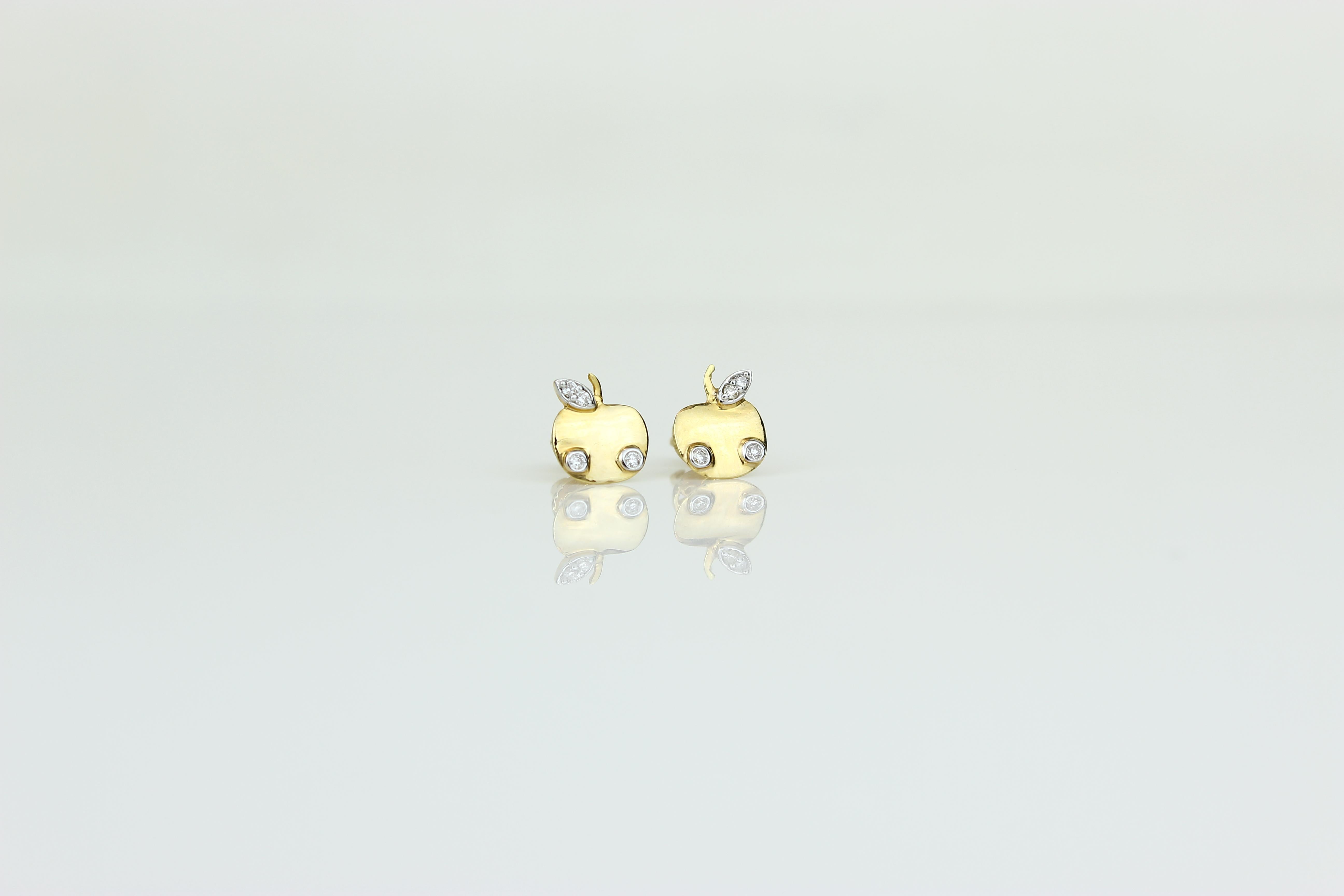 The Apple Diamond Kid Earrings are a charming and playful accessory for young fashion enthusiasts. Crafted from 18K solid gold, these earrings feature a delightful apple design adorned with shimmering diamonds. With their whimsical appeal and