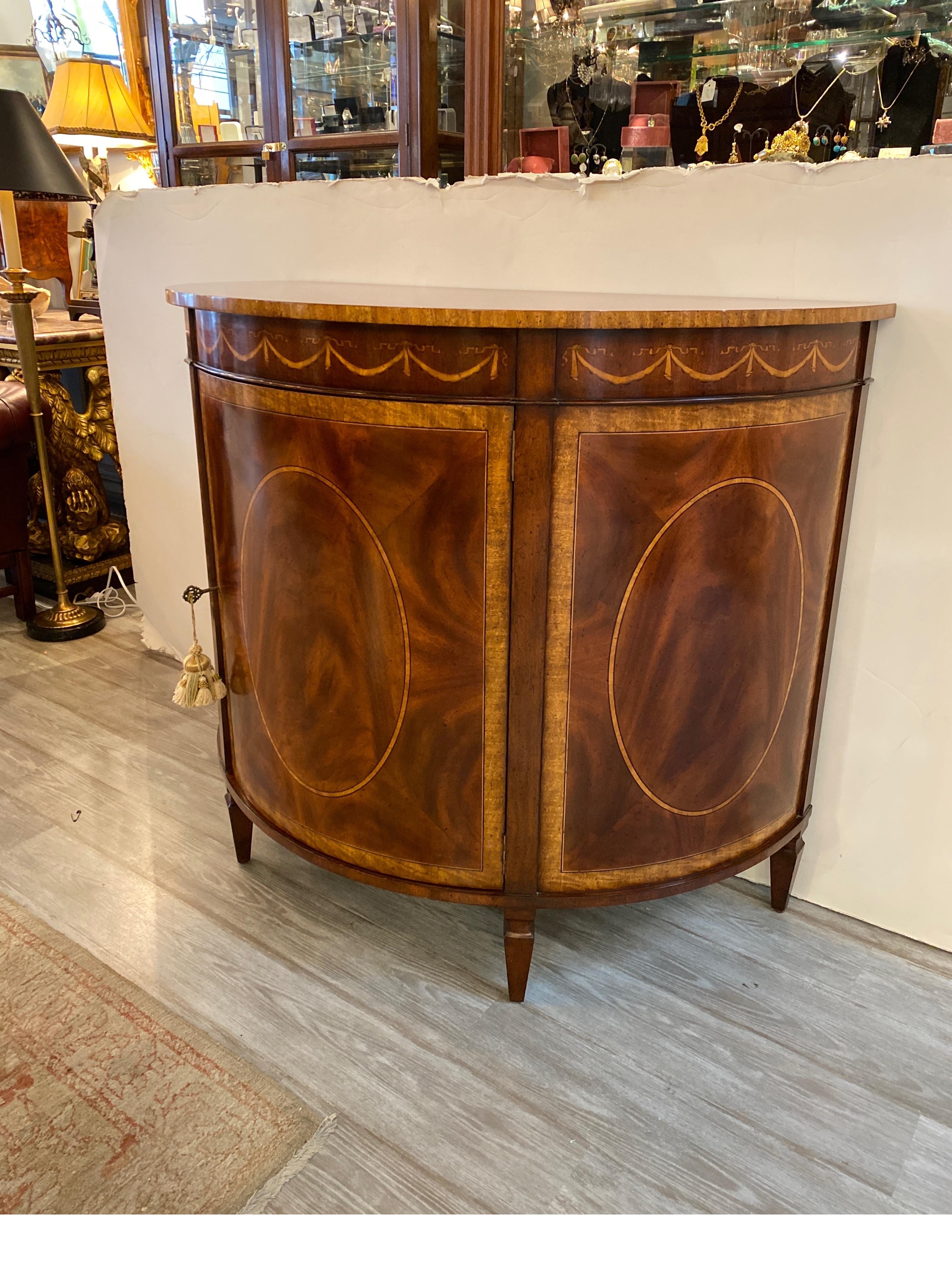 Elegant mahogany and satinwood Demi-lune cabinet with satinwood inlay. The half moon shaped top with cross banded edge, with central drawer with oval inlay on the front three panels. The door opens to reveal a removable single shelf.