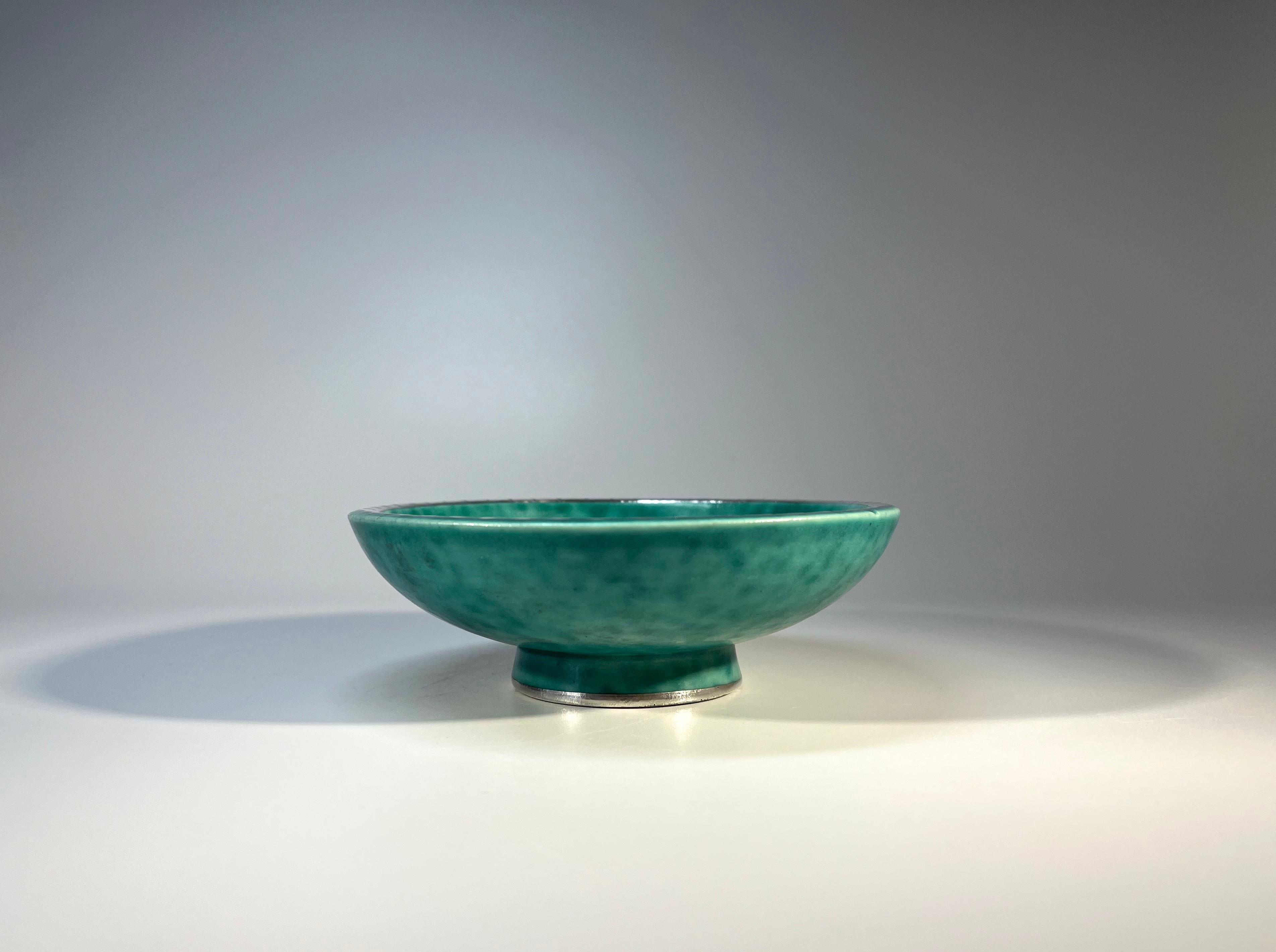 Stoneware Argenta dish by Wilhelm Kage for Gustavsberg, Sweden. 
Decorated with applied silver scalloped rim and trefoil flower sprigs  on green mottled stoneware
Circa 1960's
Stamped Gustavsberg Argenta on reverse #1094 II
Diameter 5 inch, Height