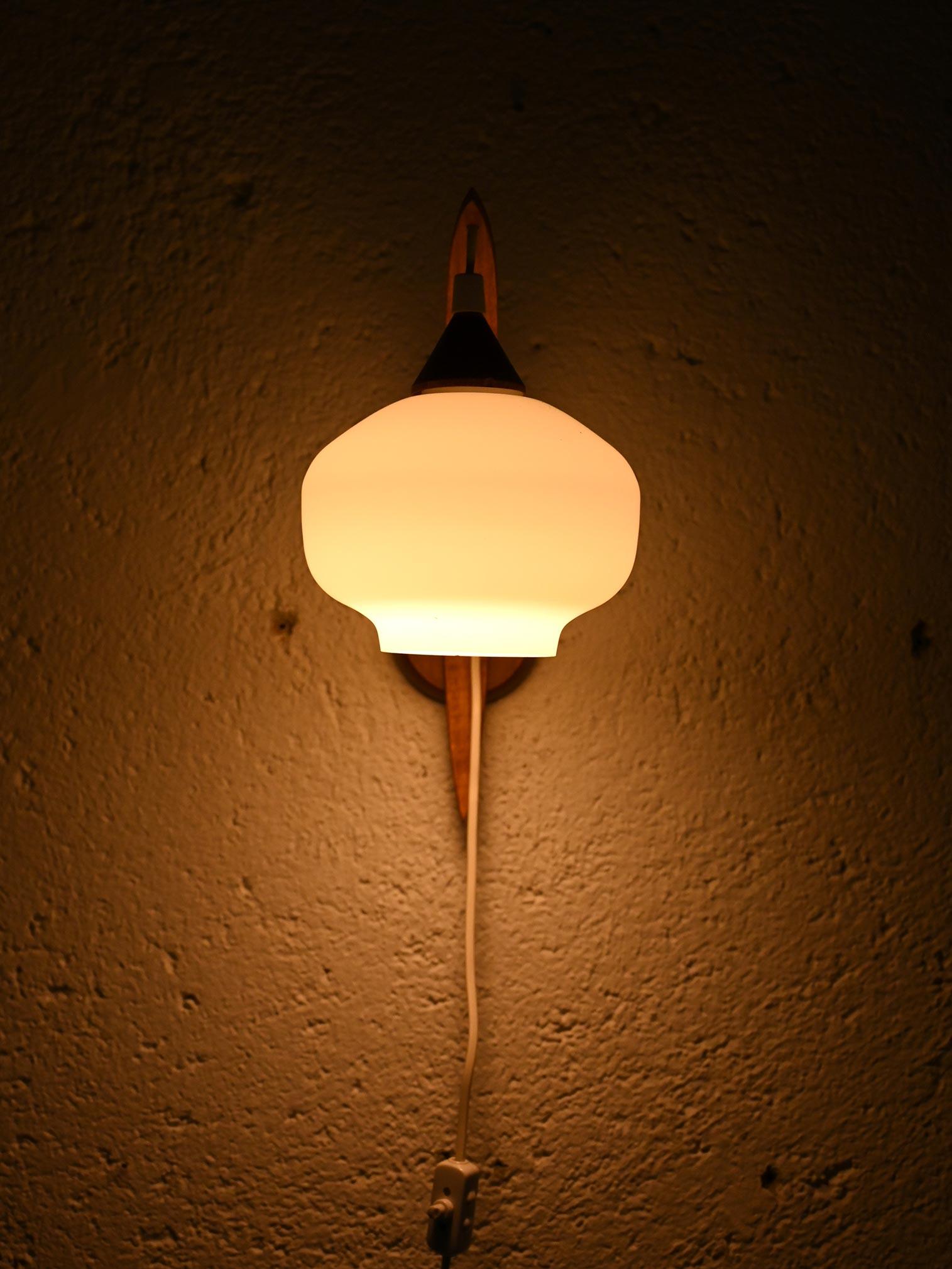 Lampada da parete in legno di teak piegato con paralume in vetro opaco. 

Buone condizioni. Potrebbe presentare dei segni del tempo. Per piacere presta attenzione alle fotografie.

AE1132
