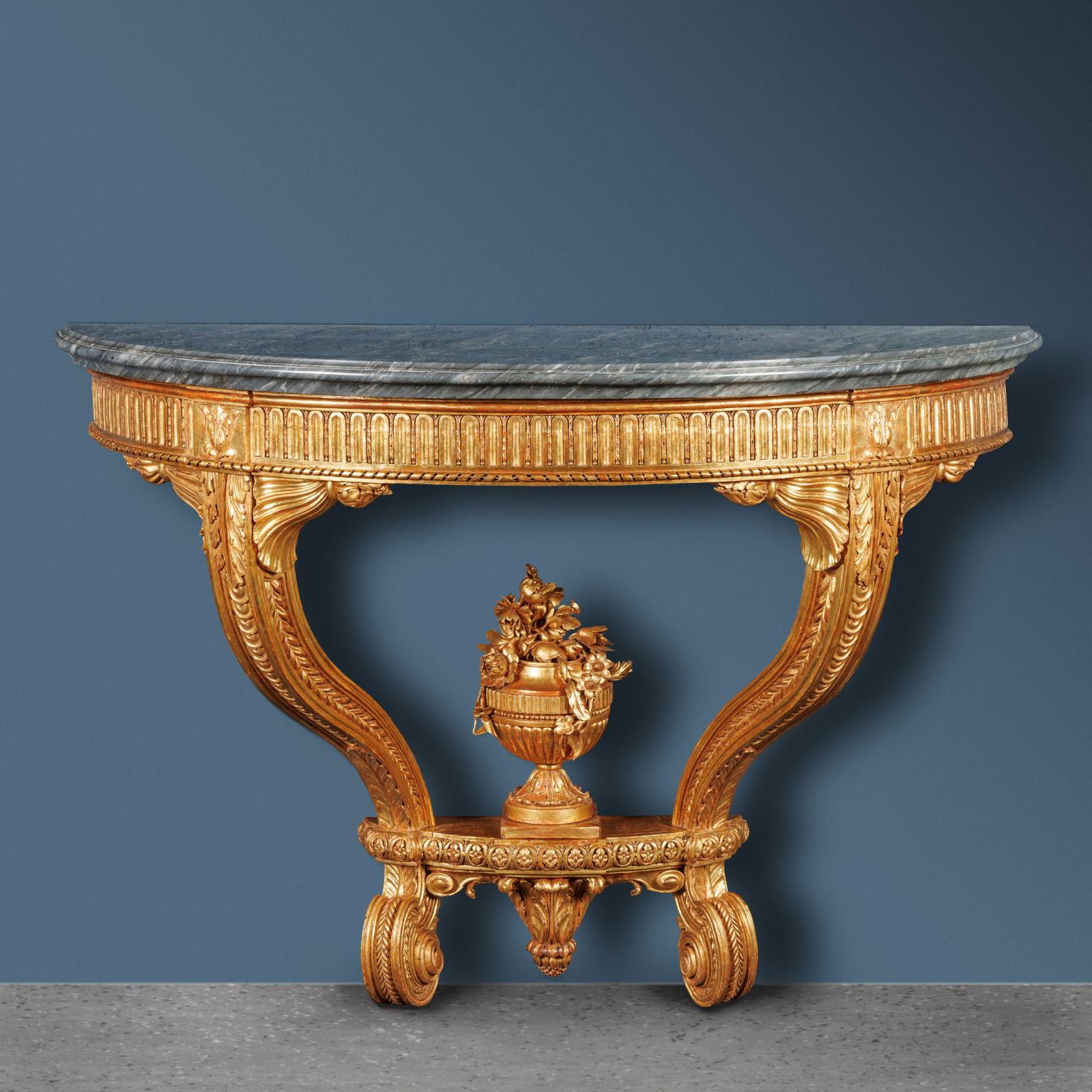 Wall table supported by two legs moved to “S”, connected to the band under the top by carved shelves; grey marble top molded on the edge.
The band is carved with pods and finished with a ribbon frame. The uprights end with two curly feet, which are