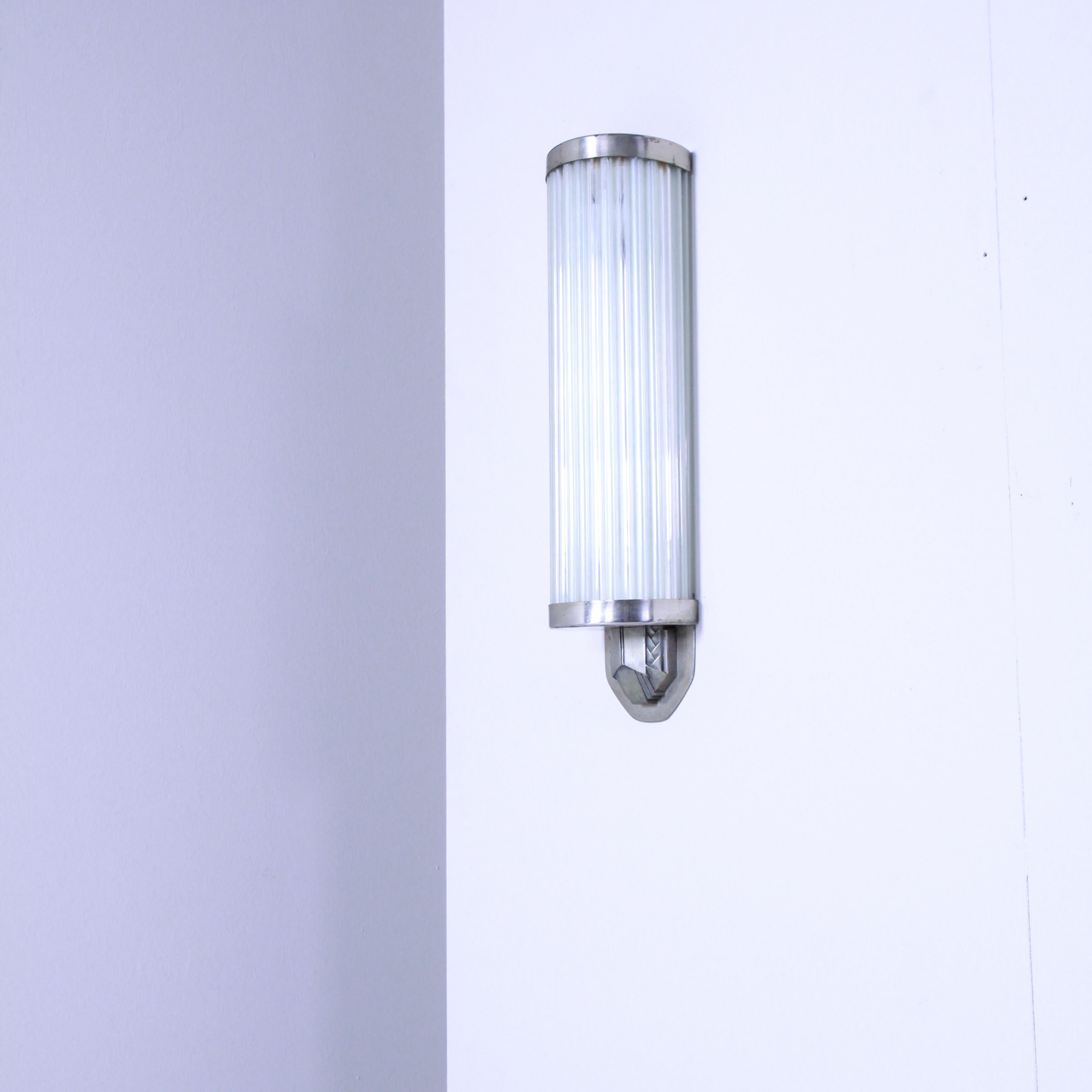 Este original aplique de pared de los años 30 encarna el estilo Art Déco con su combinación de materiales y elegantes formas geométricas. La estructura es de metal y se caracteriza por unas líneas limpias y un diseño refinado típicos de la época. El