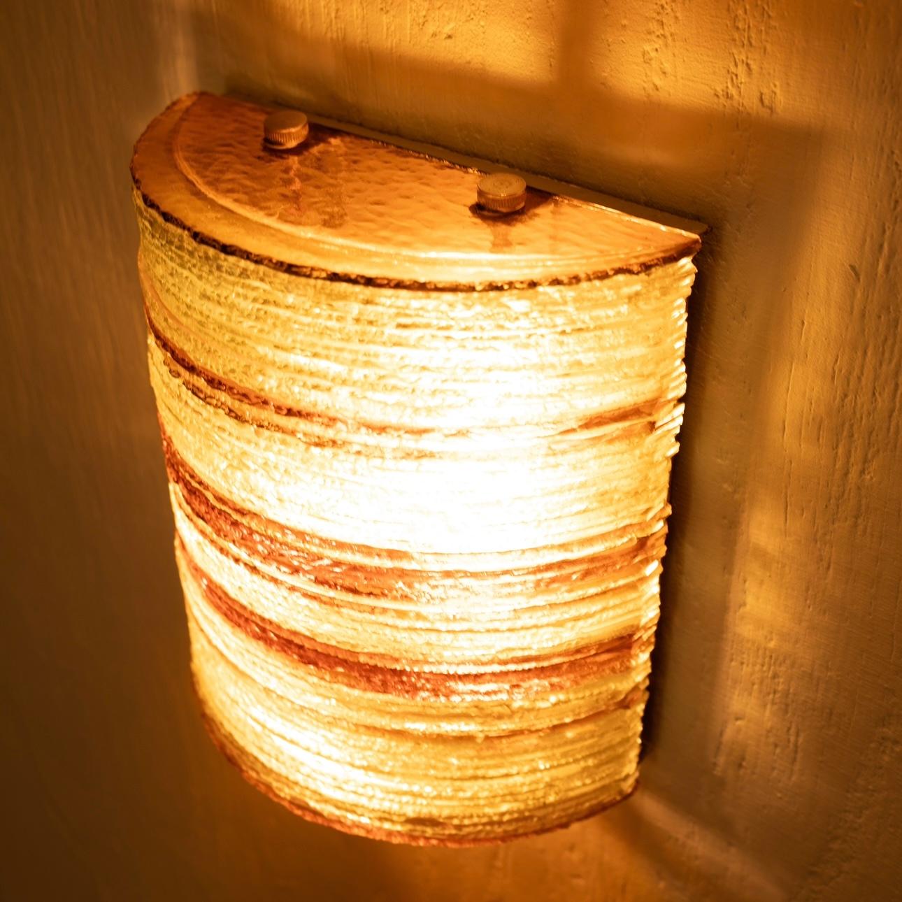 Stunning and rare wall sconce designed and produced by Albano Poli for the Poliarte Verona company of the same name in the 1960s.
It is made of thin clear and amber-colored glass stacked on top of each other and broken by hand in a crescent shape,
