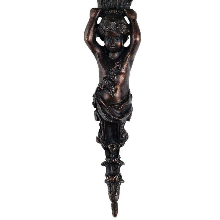 Eleve su espacio con nuestro encantador aplique mytho de tres luces con putto. Fabricada con un intrincado armazón de bronce fundido, adornado con motivos de querubines, esta lámpara añade un toque de elegancia y encanto intemporales a cualquier