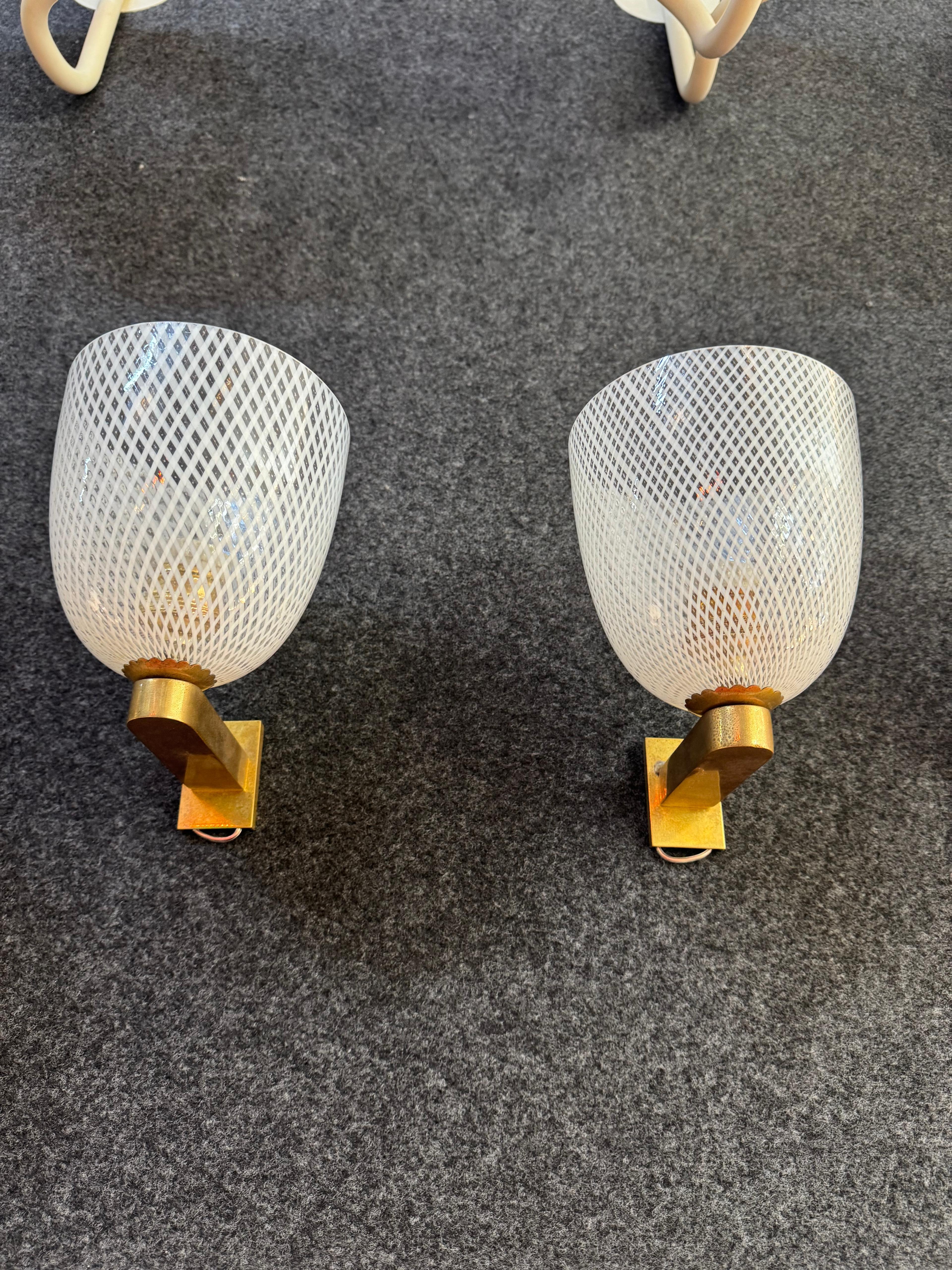 Straordinario set di 6 applique murali in vetro soffiato lavorato a reticello, firmate Barovier & Toso e risalenti agli anni '50. Questi raffinati elementi d'illuminazione incarnano la maestria del vetro artistico muranese, combinando una struttura