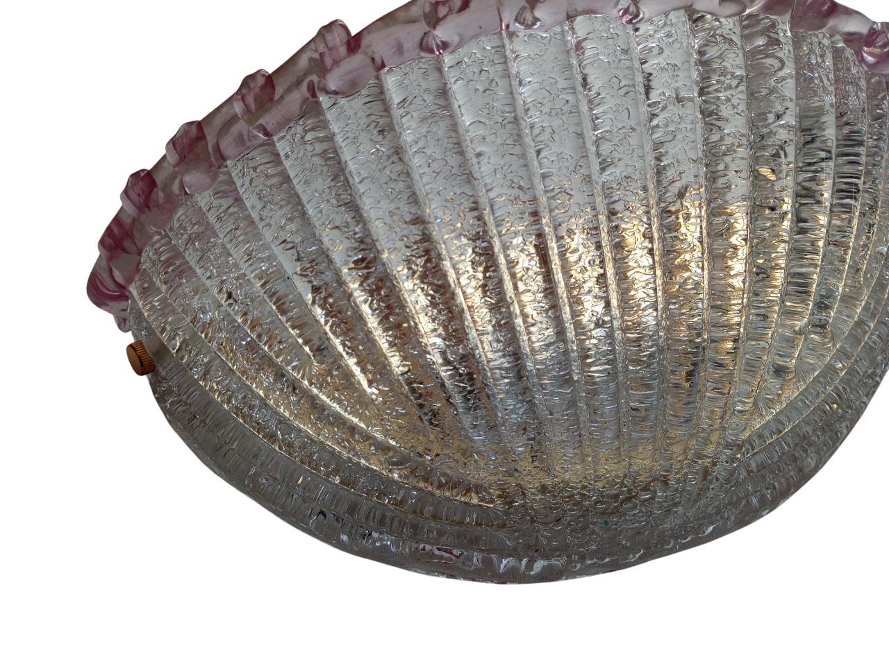 Vintage wall sconce from the 1980s made of Murano glass, measuring 40 cm wide, 17 cm deep and 17 cm high. The lampshade is made of Murano glass in a delicate pink, featuring, on the inside, a granular effect obtained with the traditional grit