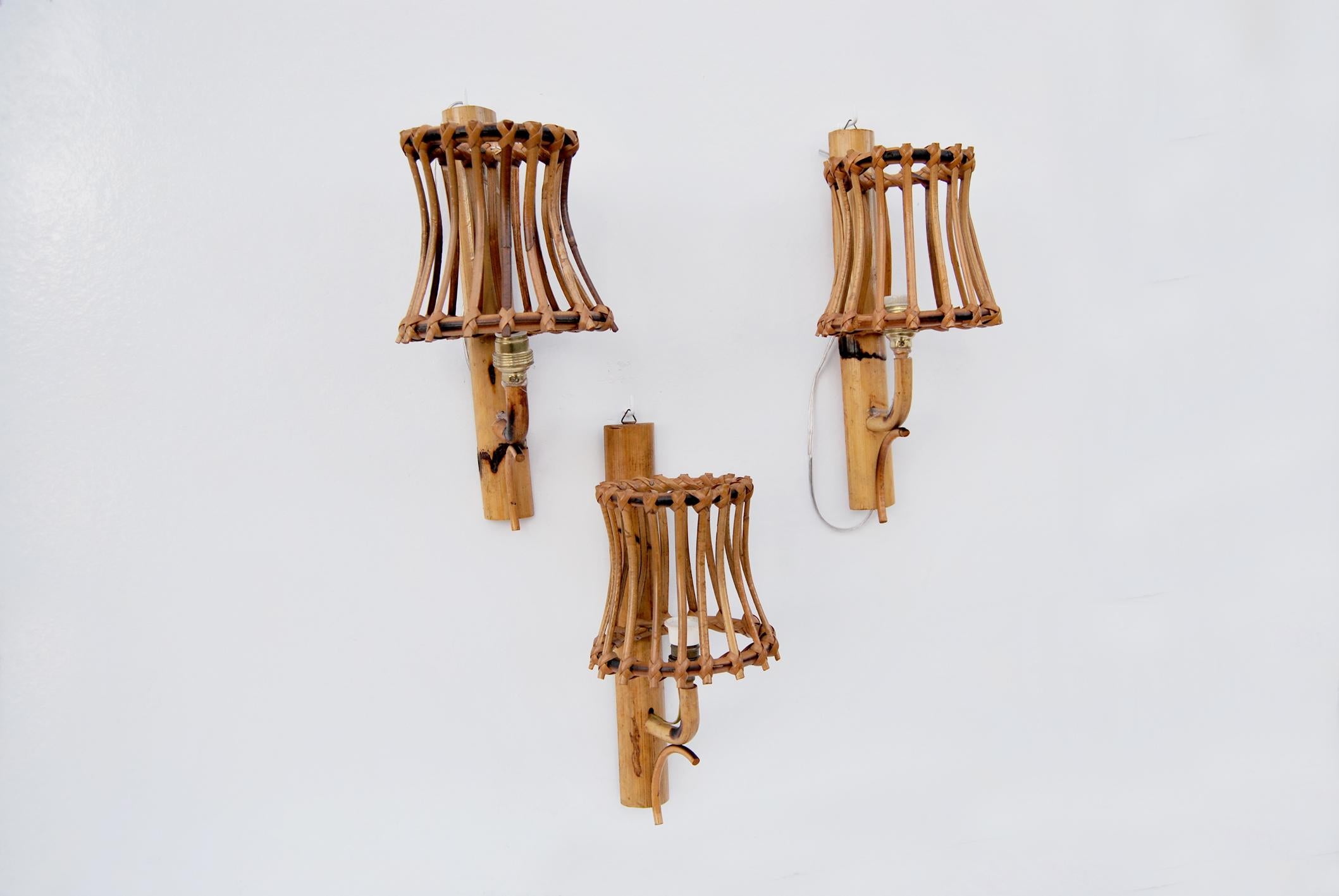 Applique in vimini e bambu' nello stile di Louis Steele, Anni' 60. 
La structure est réalisée avec de la canne de bambou étiquetée avec un motif géométrique, d'où émergent diverses cannes travaillées à la main et assemblées, toutes en rotin, qui