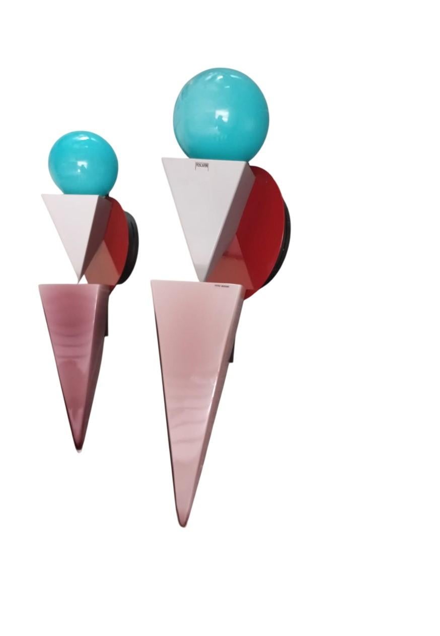 Pareja de lámparas de pared, diseñadas en 1985 por Adam T. Tihany y Joseph Mancini para Foscarini y producidas por Foscarini. Este par de apliques tiene un  diseño fuertemente geométrico y lúdico, y se titulan 