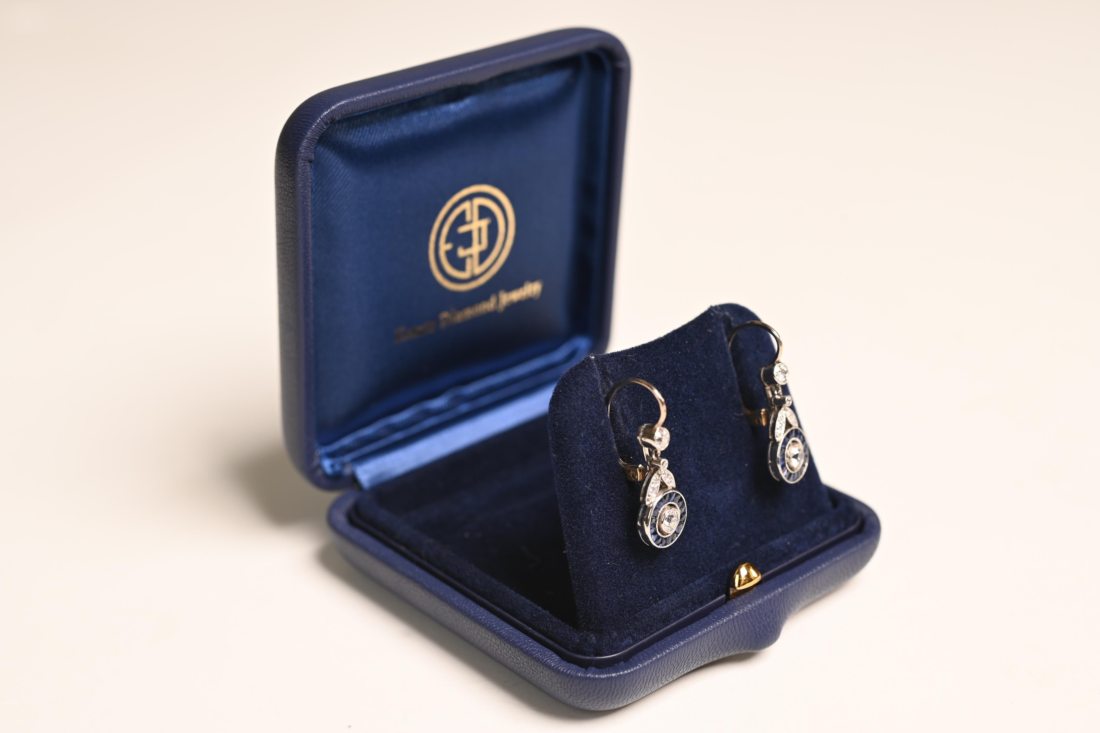 Up for auction is an exquisite pair of handcrafted hanging earrings, masterfully designed in platinum and 18k yellow gold. At the heart of each earring is a stunning old European cut diamond, weighing approximately 0.15 carats each. These dazzling