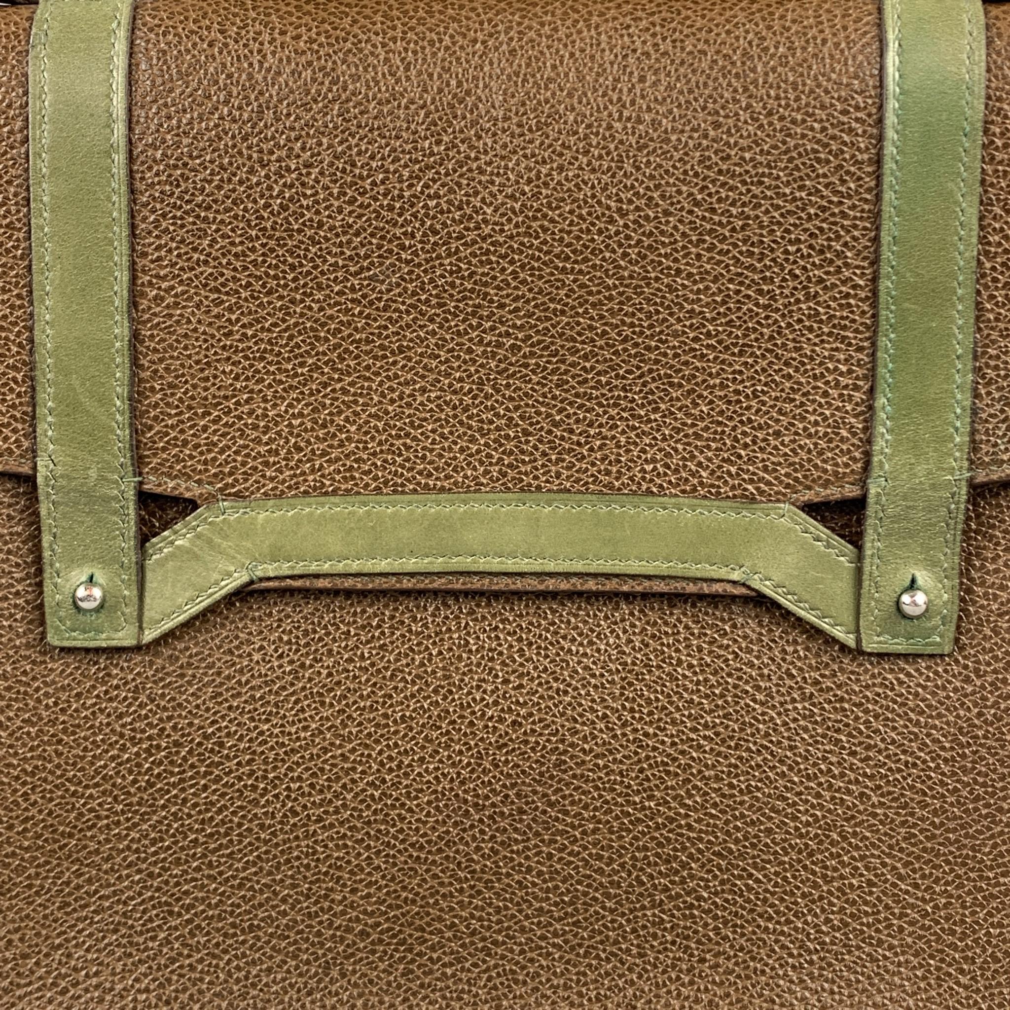 APRIL in PARIS bag comes in a brown textured leather with a olive trim featuring a top handle, inner slots, and a front button closure. Handmade in San Francisco.

Excellent Pre-Owned Condition.
Original Retail Price: