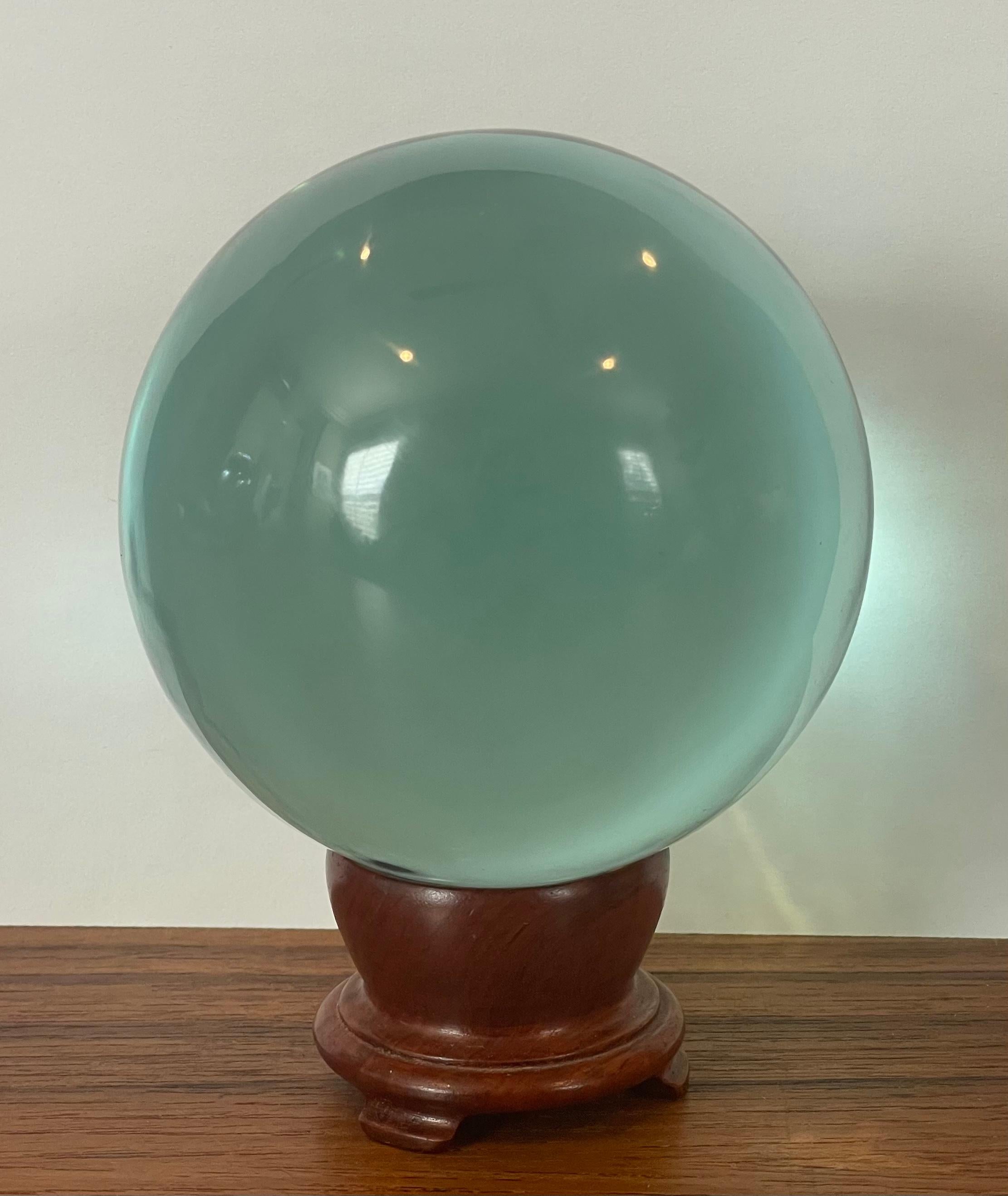 Aqua colored art Ggass orb sculpture on wooden stand, circa 1980s. The glass orb is in very good condition with no chips or cracks and measures 3