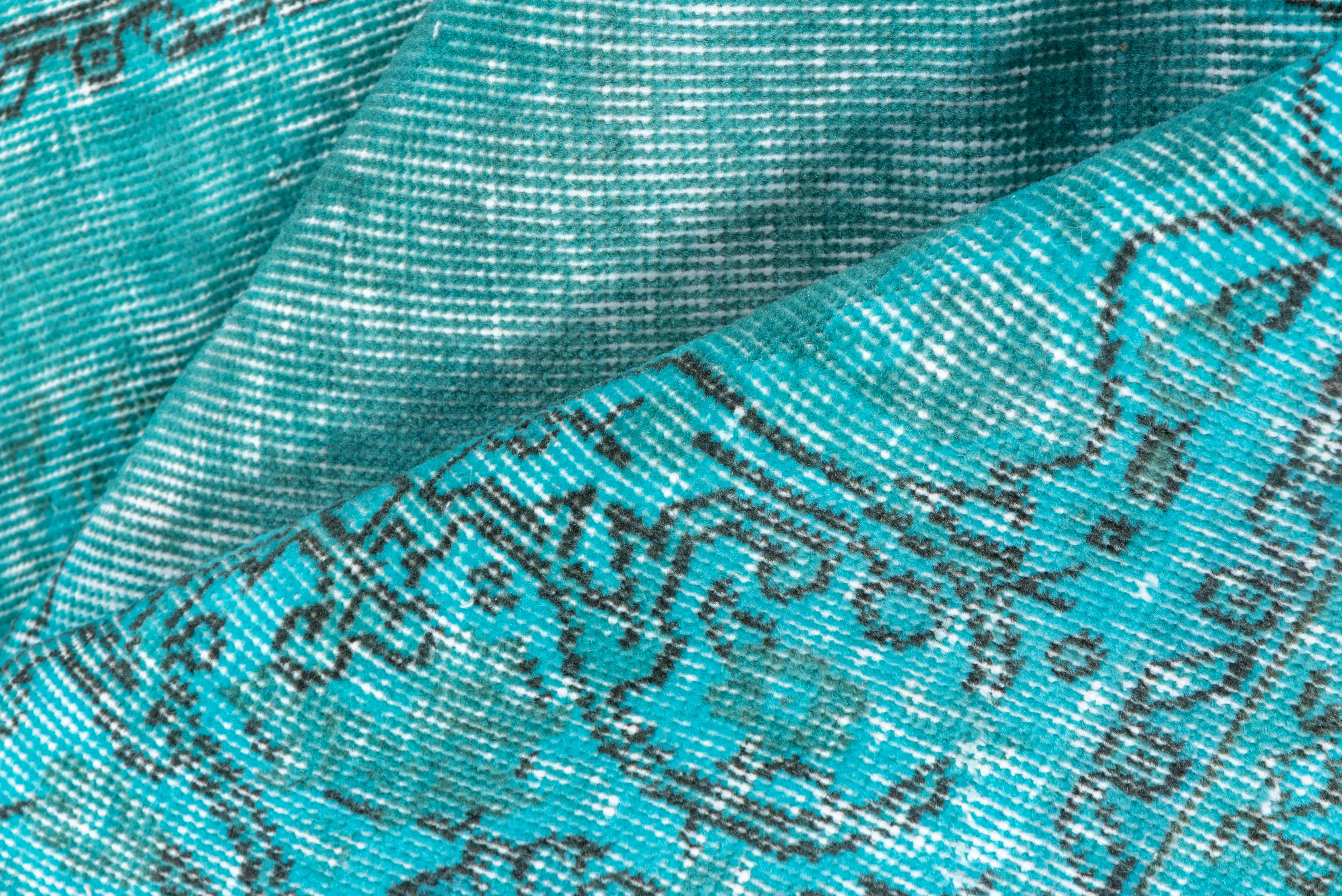 Ce tapis spartiate turc surteinté bleu aqua et turquoise présente un motif défini par l'usure au-delà de la détresse générale. Des bandes verticales et horizontales de couleur blanc cassé se croisent près du centre. Shabby Chic conditionne et peut