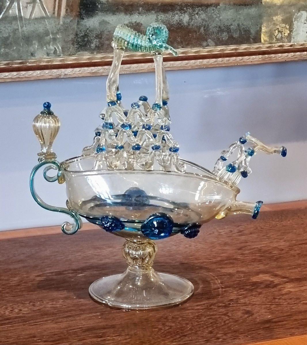 Extraordinaria escultura de cristal soplado de Murano de un velero estilizado, realizada en las últimas décadas del siglo XIX siguiendo el modelo de los aguamaniles renacentistas. Este tipo de objeto, de evidente valor ornamental, se utilizaba como