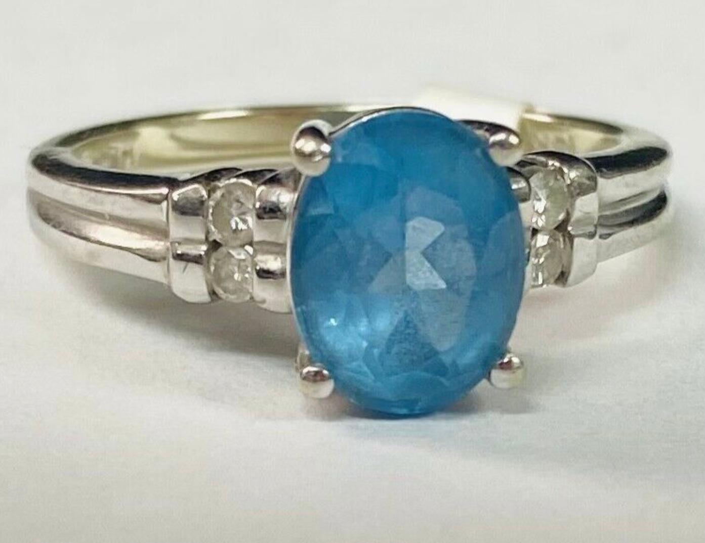 14k white gold aquamarine and diamond ring, 4.25 Grams TW. The dimensions of the oval aquamarine are approximately 9 mm x 6 mm. The ring has four round single cut diamonds. Marked 14k. Approximate size 7.