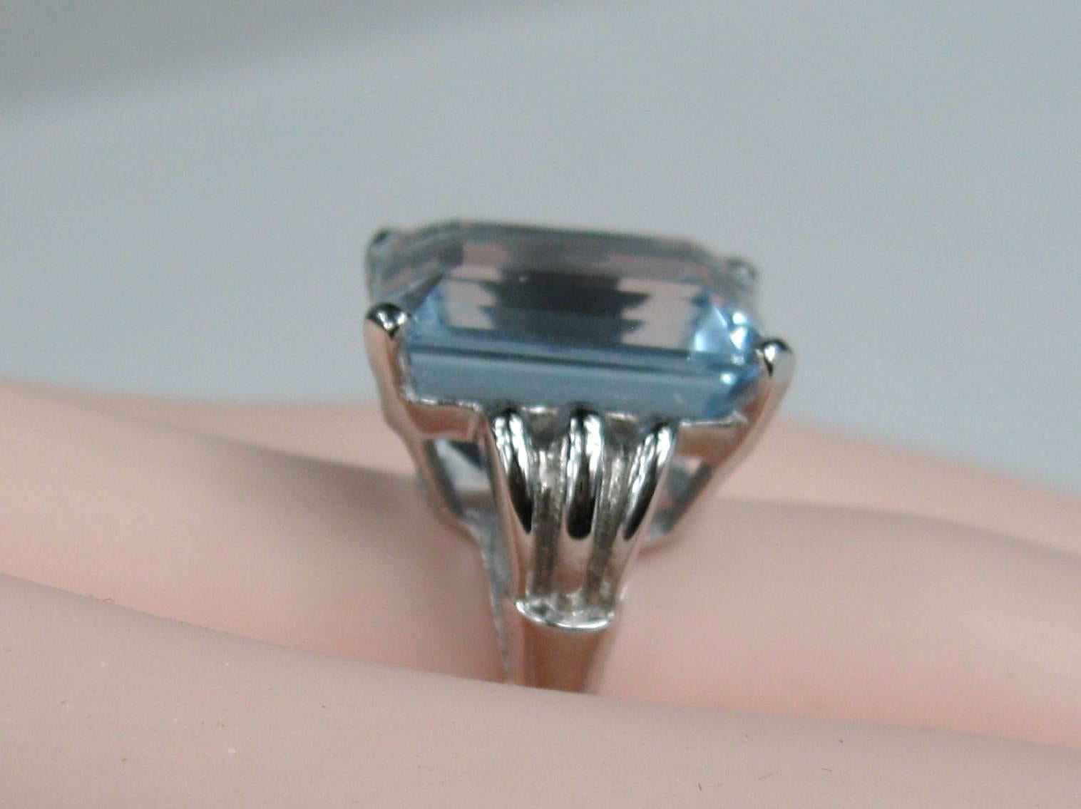 Simply stunning on this 14K White Gold Emerald Cut Aquamarine Engagement Ring. Large 13.75 Carat Octagonal cut aquamarine set in 14K white gold. Step Cut. Color Greenish Blue. Stone measures 14.85 x 14.06 x 9.37 Per GIA report. The ring is a size