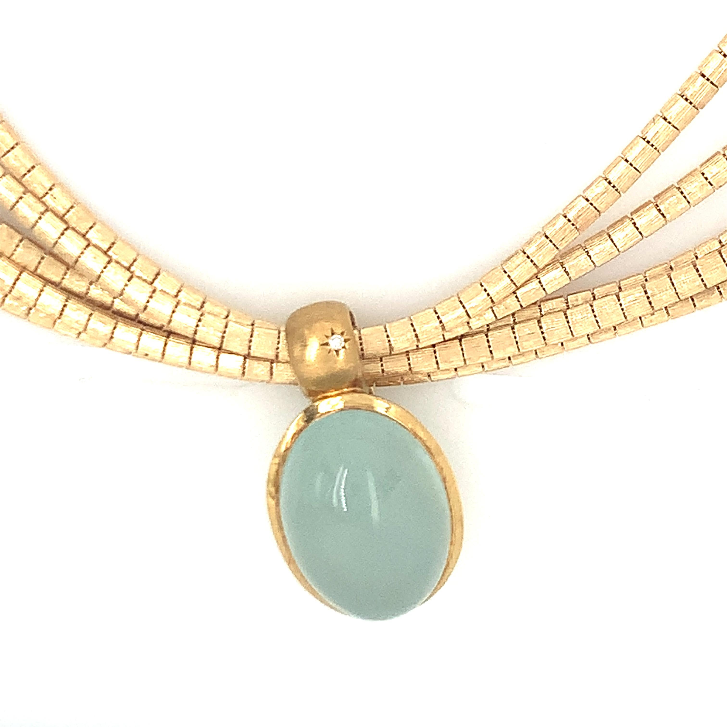 One aquamarine 18K yellow gold pendant / necklace featuring one oval sugarloaf cabochon aqua weighing 22 ct. with one star-set round brilliant cut diamond accent. Attached to a 14K yellow gold multi-strand, bamboo form link necklace measuring 22