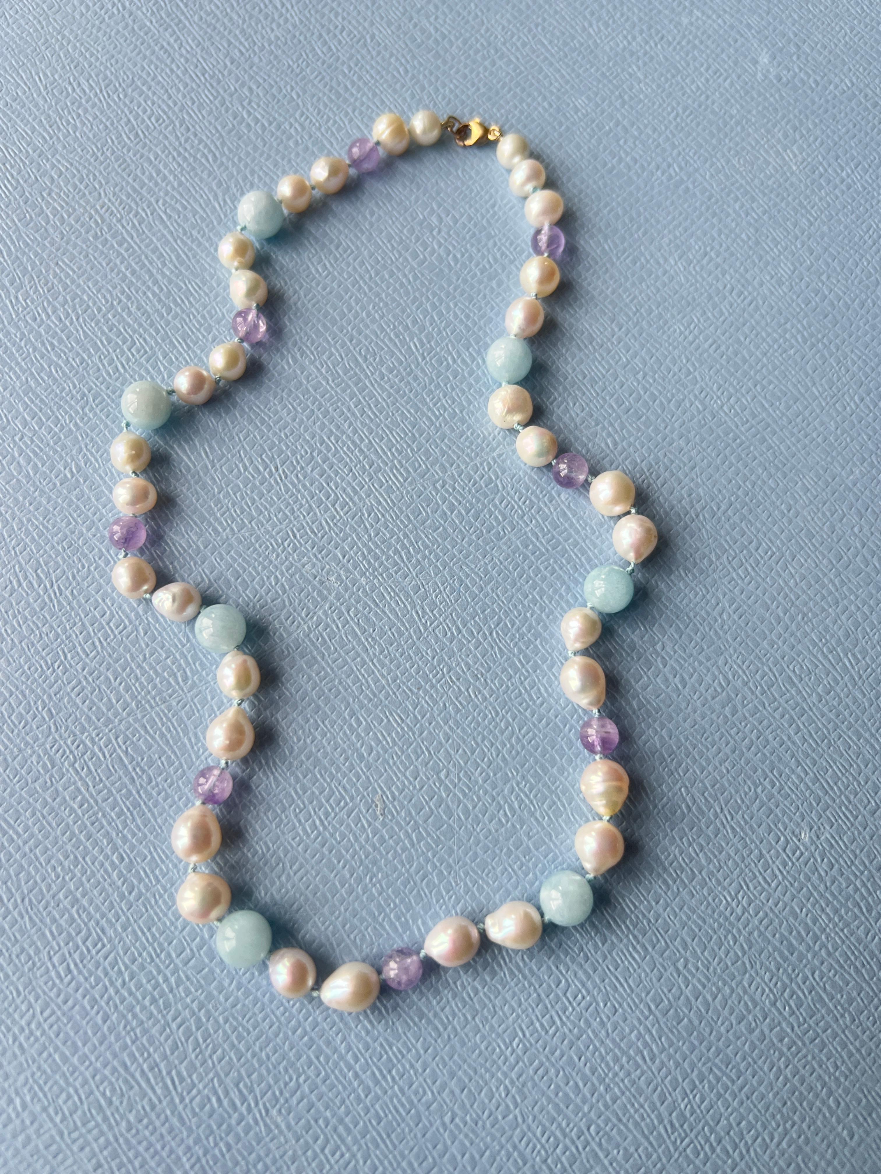 Collana girocollo con perline di acquamarina, ametista e perla - Gioielli pastello con più pietre di J DAUPHIN

Un luminoso girocollo di perline di J DAUPHIN, che combina acquamarina, ametista e perle bianche in una morbida palette di colori