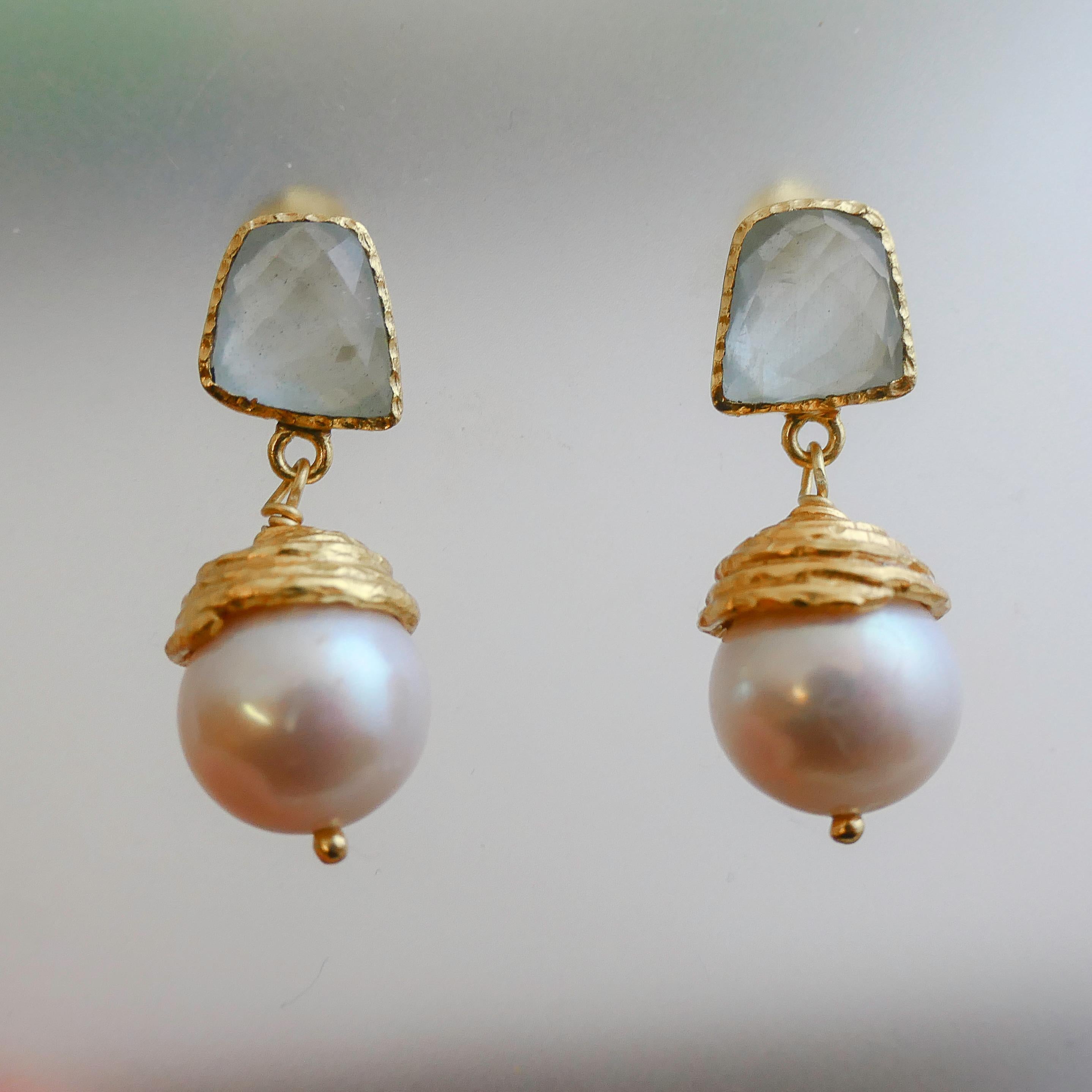 L'acquamarina a forma libera è incastonata in argento placcato oro. Una perla d'acqua dolce di 12 mm è racchiusa sotto gli orecchini a perno. La lunghezza degli orecchini è di 3,4 cm.