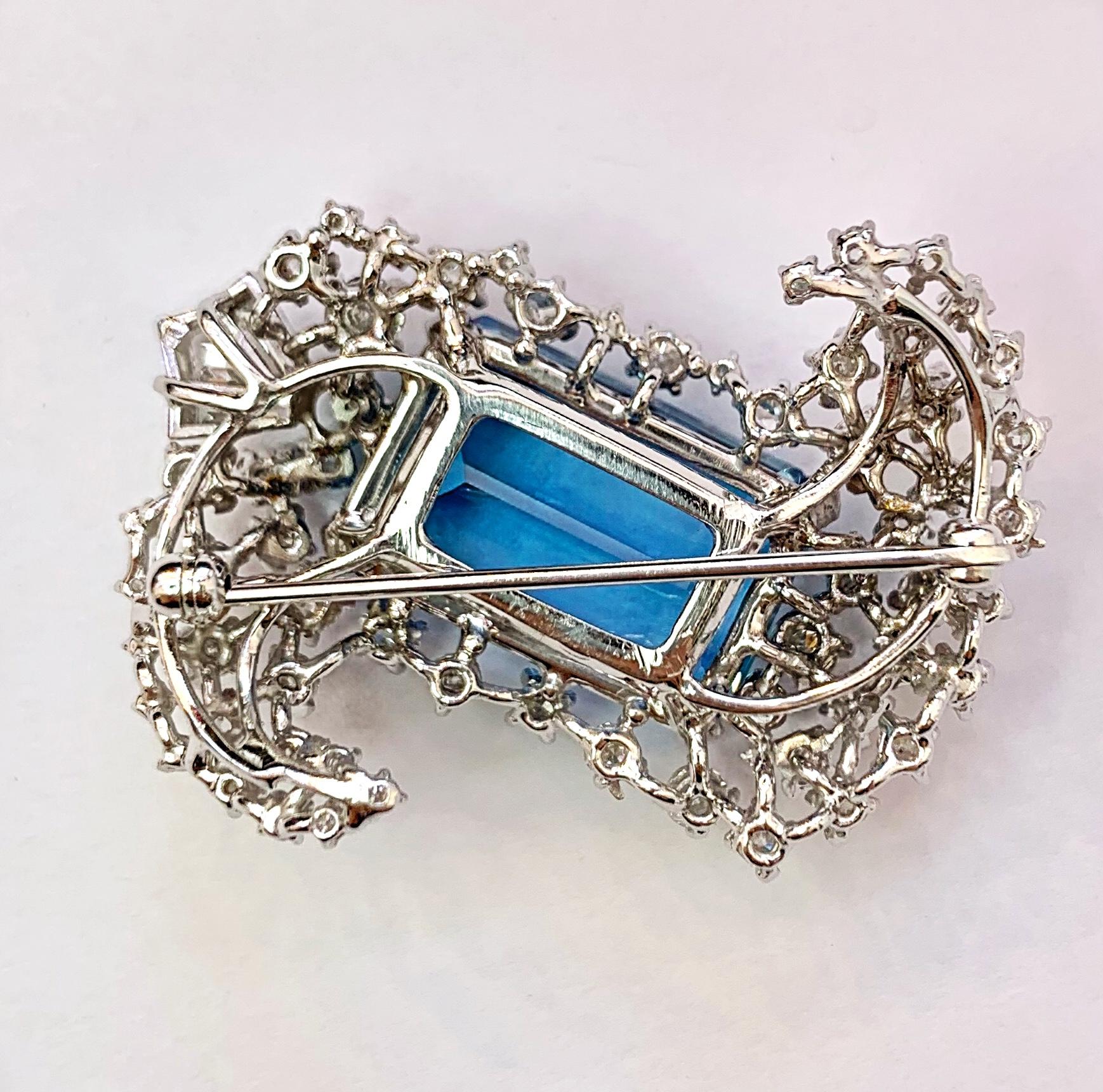 Gorgeous 14K white gold blue aquamarine brooch circa 1940's. The emerald cut aquamarine weighs 22.57cts and it is surrounded by 66 brilliant cut, baguette cut and kite shape diamonds with a total weight of approximately 3.41cts. It measures 42mm
