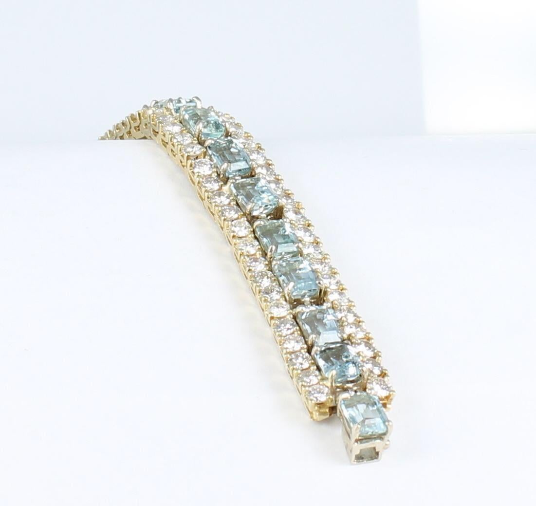Eighteen icy cool emerald-cut aquamarines, 35.0 carats total weight, trail down the center of this 18 karat yellow gold bracelet.   On either side of the aquas is a row of diamonds, 12.0 carats total weight.  The very best of blue is displayed in