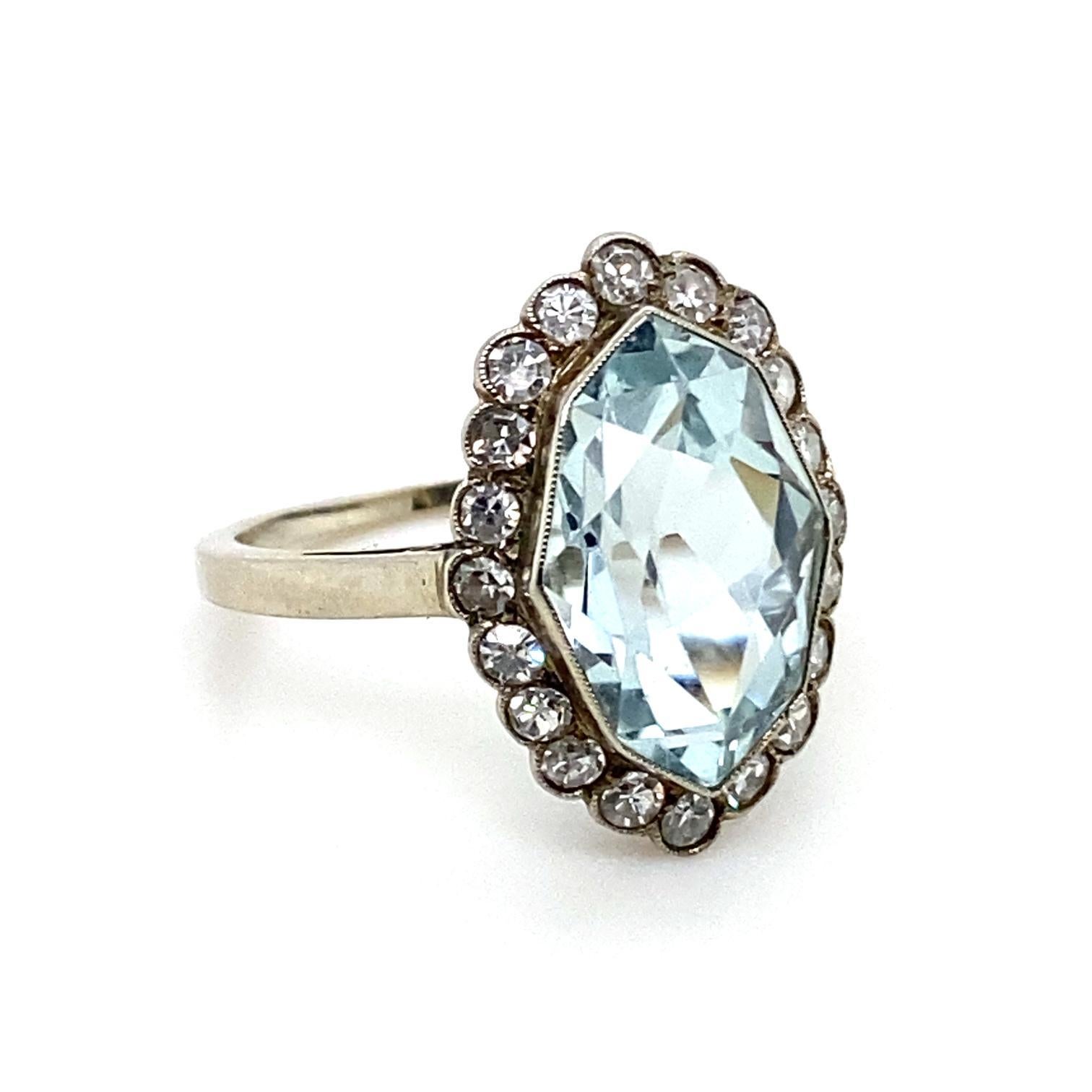 An aquamarine and diamond cluster 14 karat white gold engagement ring.

This handmade piece is centrally set with a mixed oval cut aquamarine of 4.93cts approximately within a milgrain set bezel, surrounded by a cluster of 19 single cut diamonds