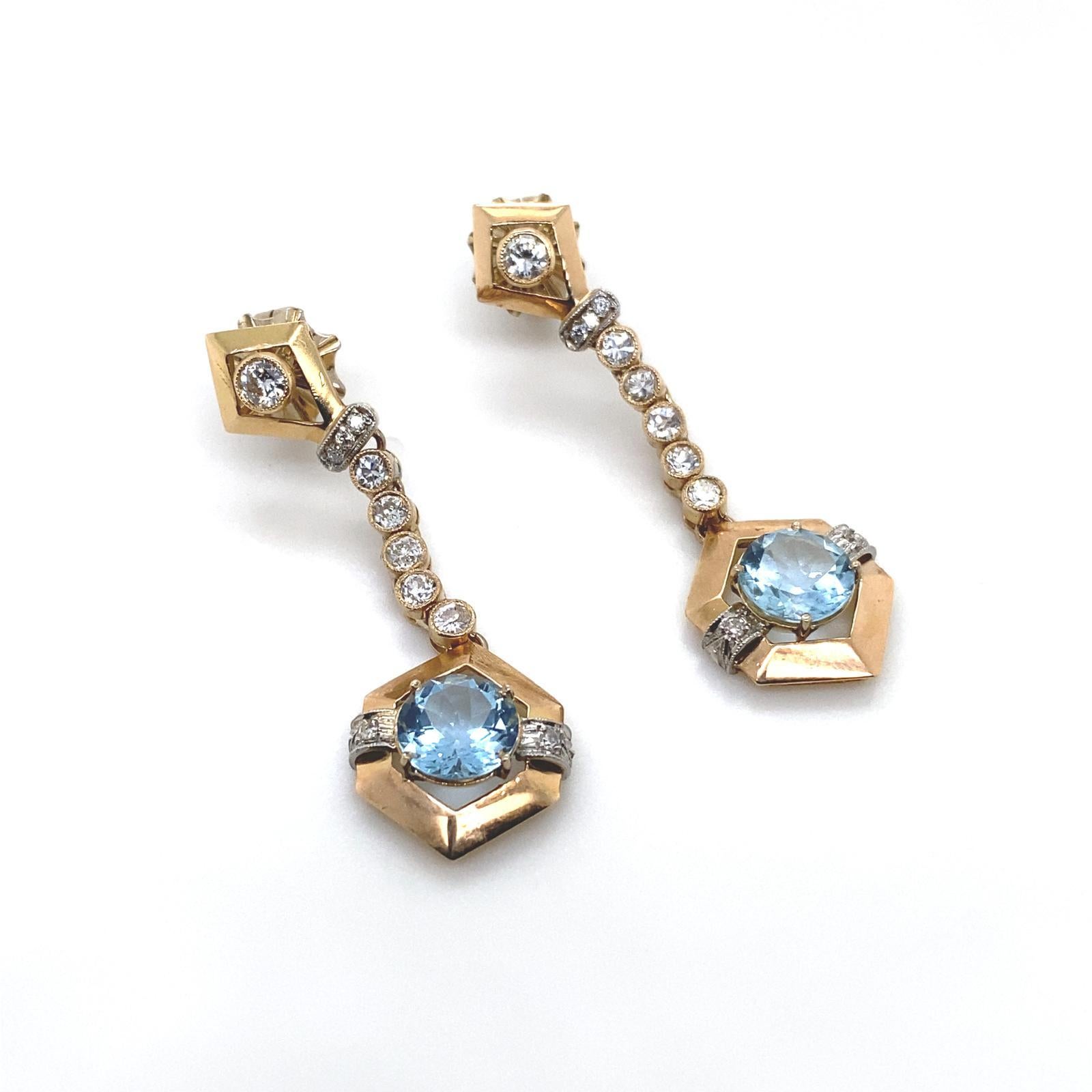 Un paio di orecchini a goccia con acquamarina e diamanti in oro giallo 18 carati.

Questi orecchini in oro giallo hanno la parte superiore a forma di aquilone con un singolo diamante rotondo taglio brillante incastonato che sospende una fila di