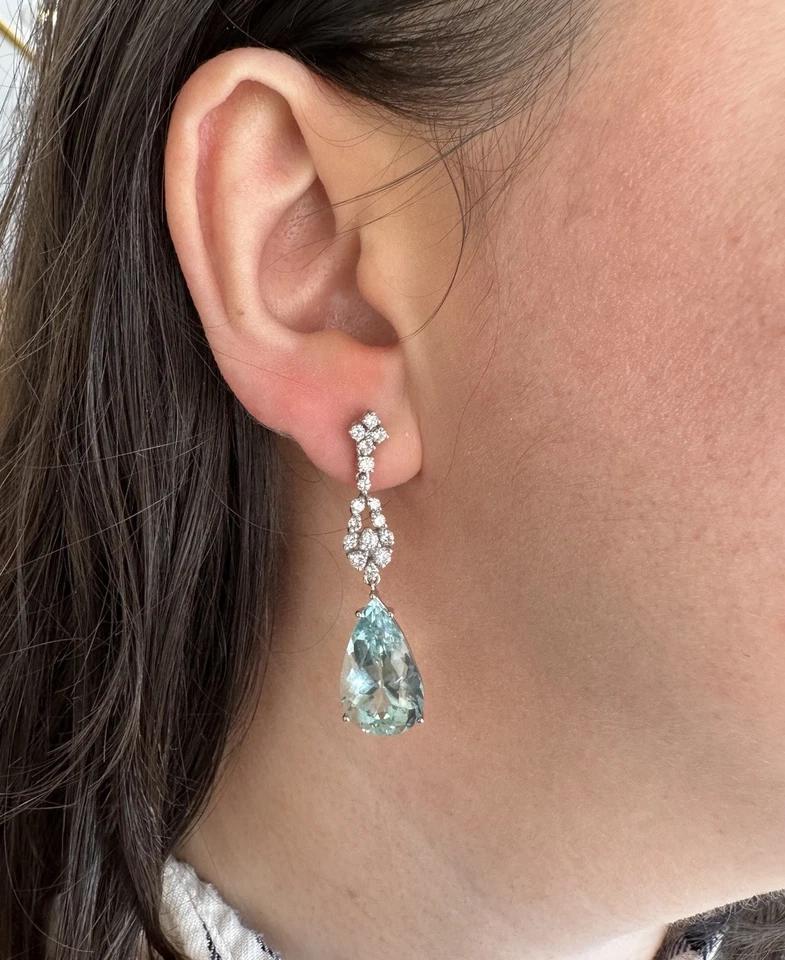 Aquamarine and Diamond Drop Earrings in 18k White Gold 

Natural Aquamarine and Diamond Earrings features two Pear-shape Aquamarines, each weighing approximately 11.00 carats, dangling from clusters of Round Brilliant Diamonds, all set in 18k White