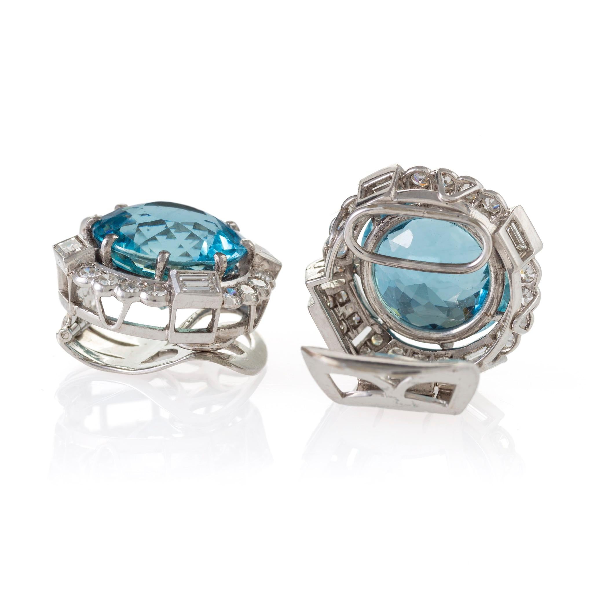 These fancy-cut aquamarine and diamond clipback earrings are mounted in platinum and date from the mid-20th century. Their circular-fancy-cut aquamarines, weighing approximately 8.35 and 9.35 carats, are each set within a frame of round