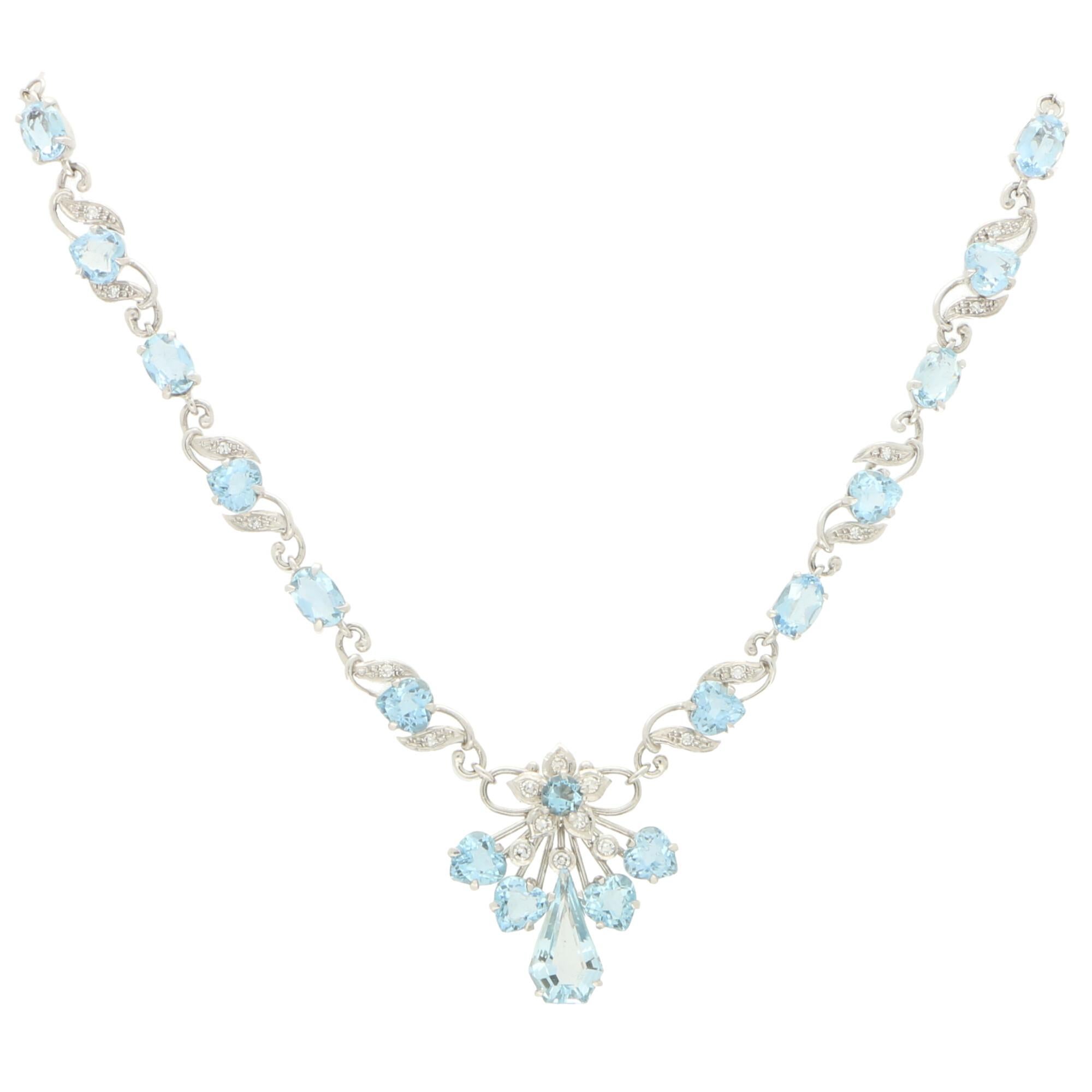 An elegant filigree aquamarine and diamond necklace set in 18k white gold. 

The focus is a spray of aquamarines set below a floral depiction on 18k white gold wirework. A centrally set shield cut aquamarine is shouldered with two heart shaped