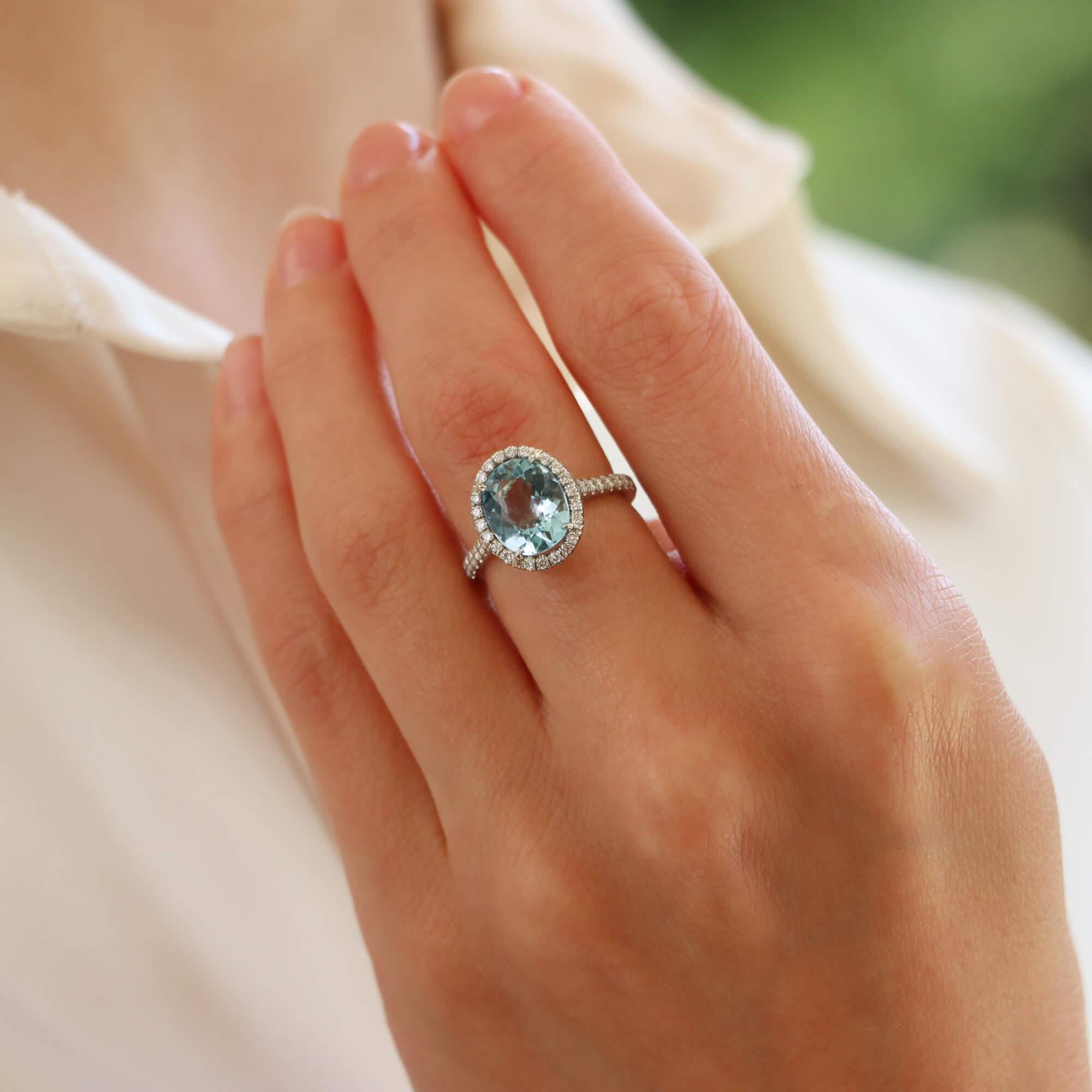  A beautiful aquamarine and diamond halo ring set in platinum.

The ring centrally features a beautiful vibrant blue oval cut aquamarine surrounded by a halo of 22 round brilliant-cut diamonds. Each shoulder is further accented with 10 round