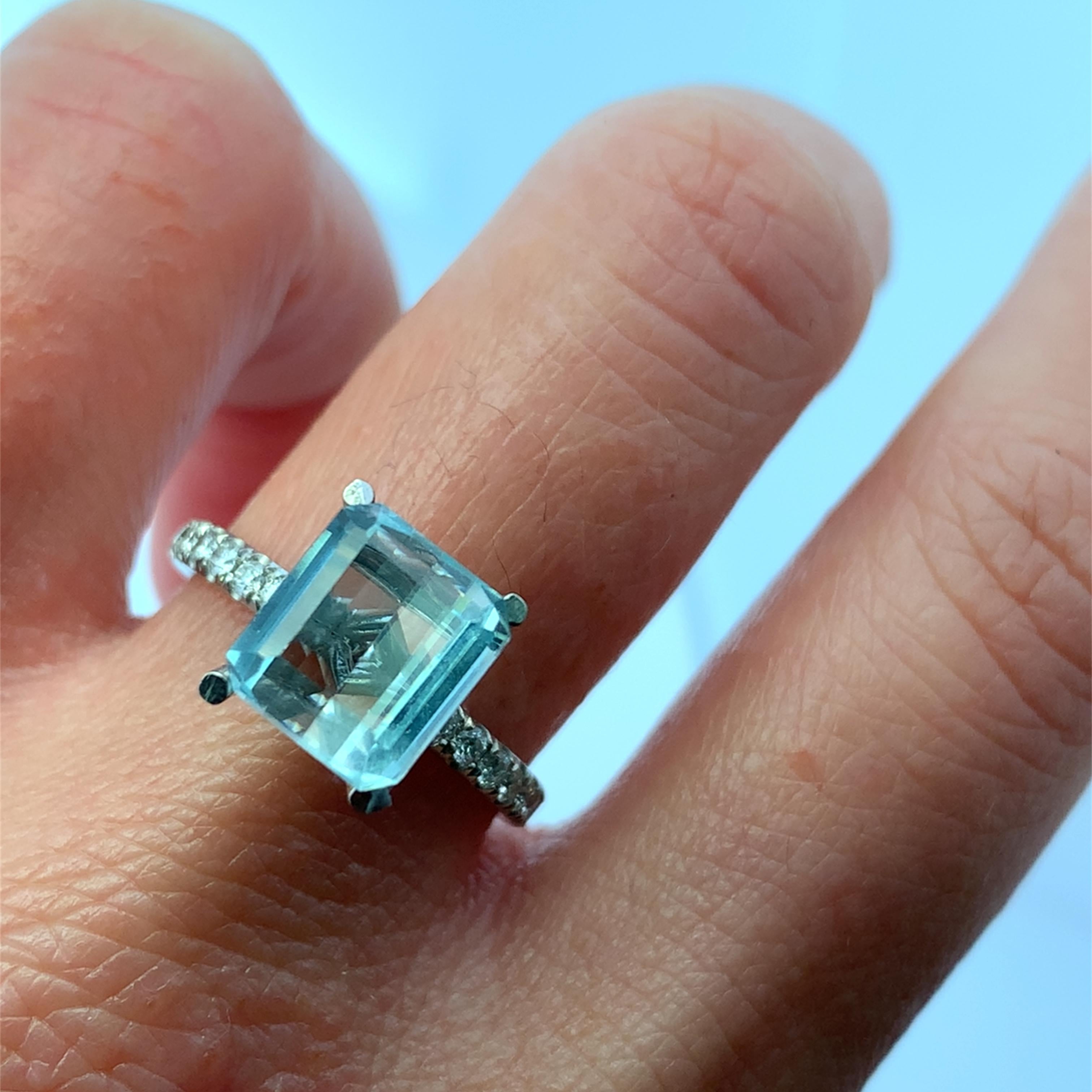 Cette magnifique bague de 1,65ct en forme d'émeraude, composée d'une aigue-marine bleue, présente une pierre rectangulaire captivante, entourée d'un halo de diamants cachés 0,70ct F VS1 et d'un anneau délicat orné d'accents étincelants. Parfait pour