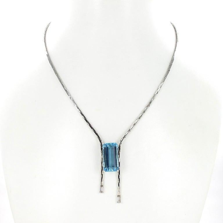 This sleek and stylish necklace in 18 karat white gold is set with one emerald-cut aquamarine of approximately 14.00 carats. Framed by a cobra chain, each end of which is set with a baguette-cut diamond of G/H colour and vs2 clarity, total weight