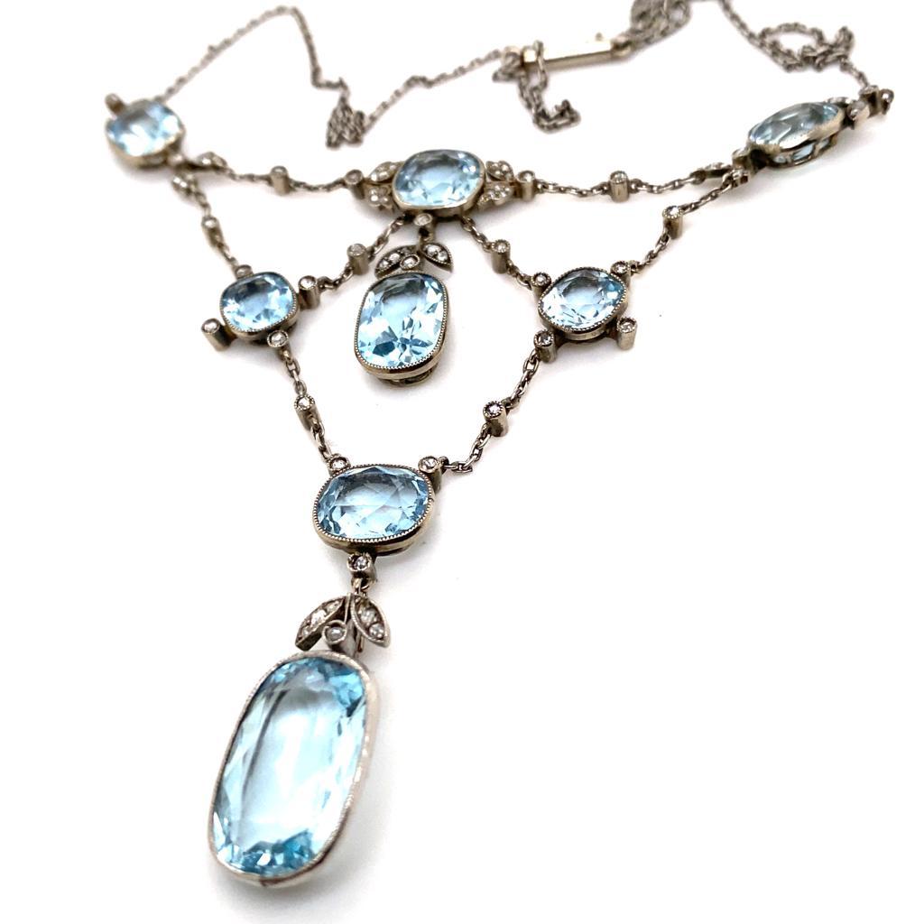 An aquamarine and diamond necklace platinum, circa 1900.

This elegant necklace comprises of beautifully sweeping scrolls festooned with eight cushion cut aquamarines of varying sizes, interspaced with bezel and grain set floral diamond set tops and