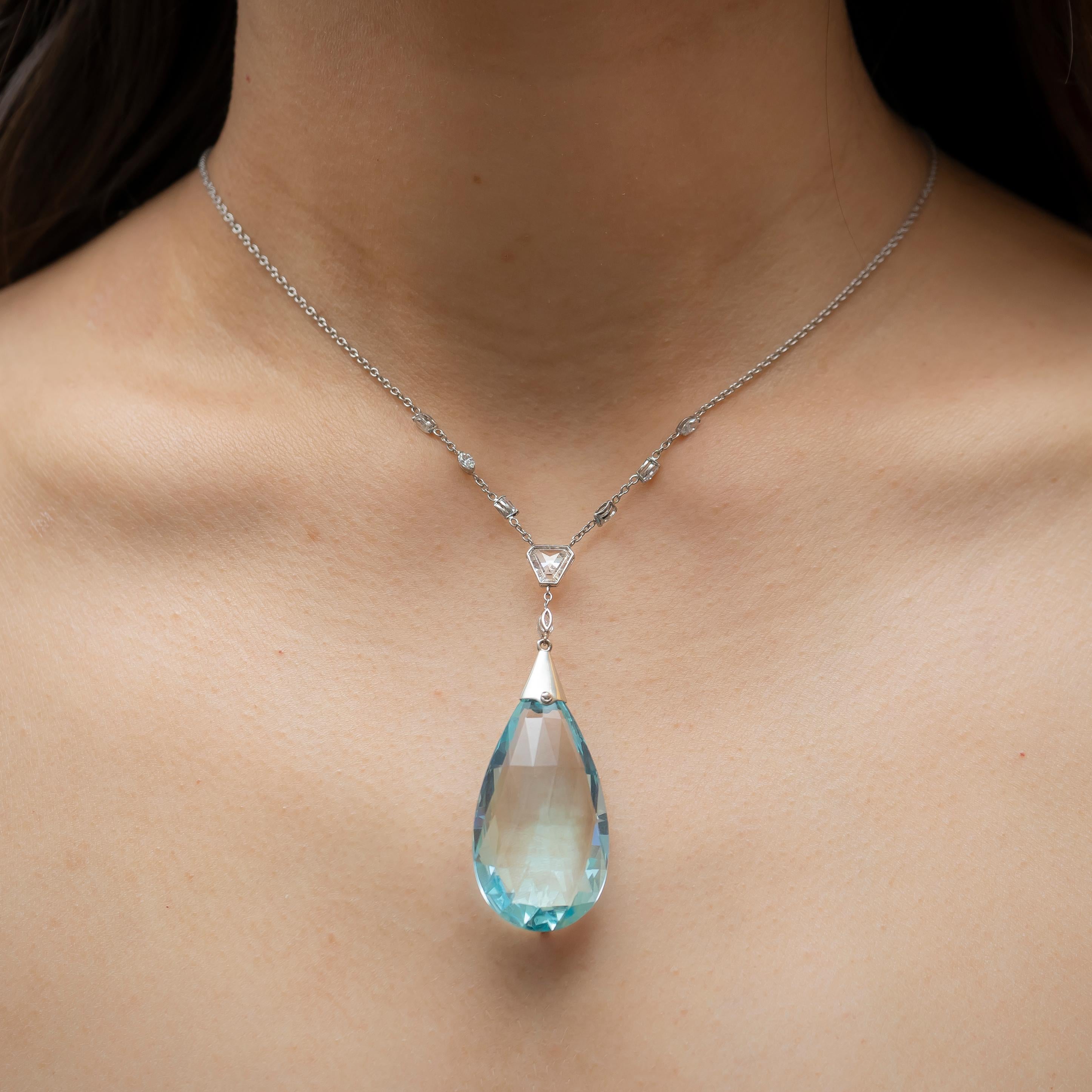 An aquamarine and diamond pendant with a drop shape briollette-cut aquamarine, with a white gold cap, set with a rose-cut diamond, with millegrain decoration, suspended from a polygonal shaped diamond and a marquise-cut diamond, on a white gold