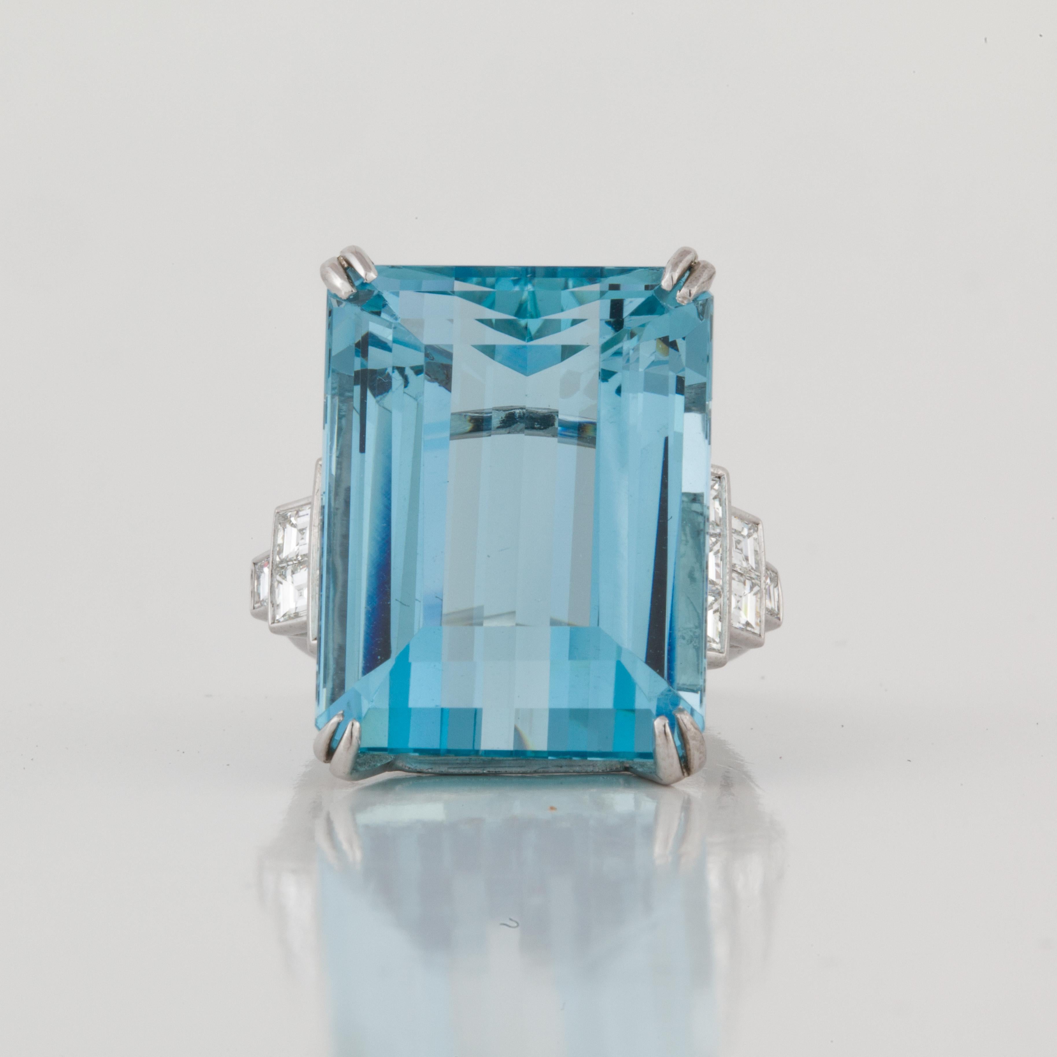 This cocktail ring features an emerald-cut aquamarine accented by step cut diamonds, set in platinum.  The ring is marked 