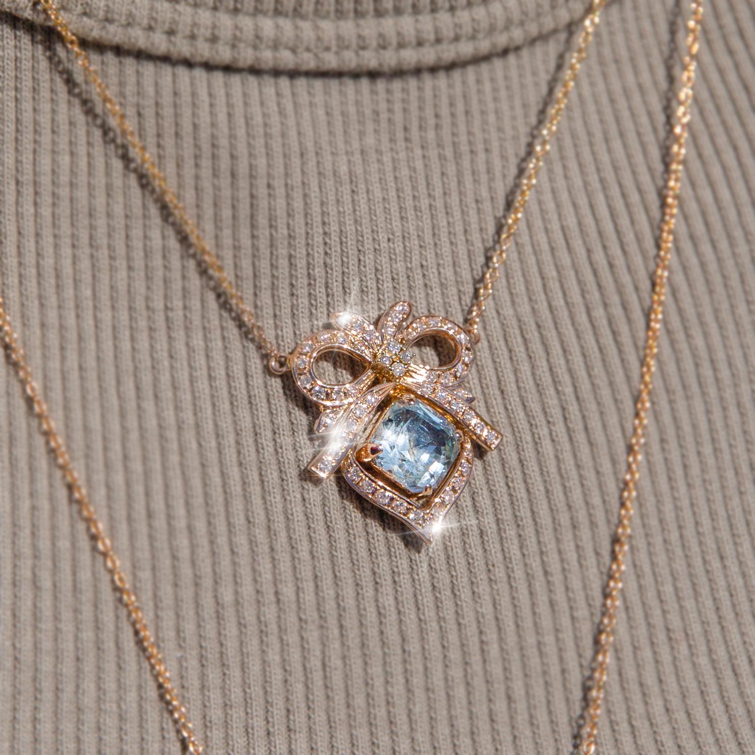 Lovingly crafted from a 1960s necklace is this reinvented jewel made with an enchanting light blue emerald cut aquamarine resting in a gorgeous 14 carat gold bow adorned with fifty-three round brilliant cut diamonds attached to a 9 carat gold