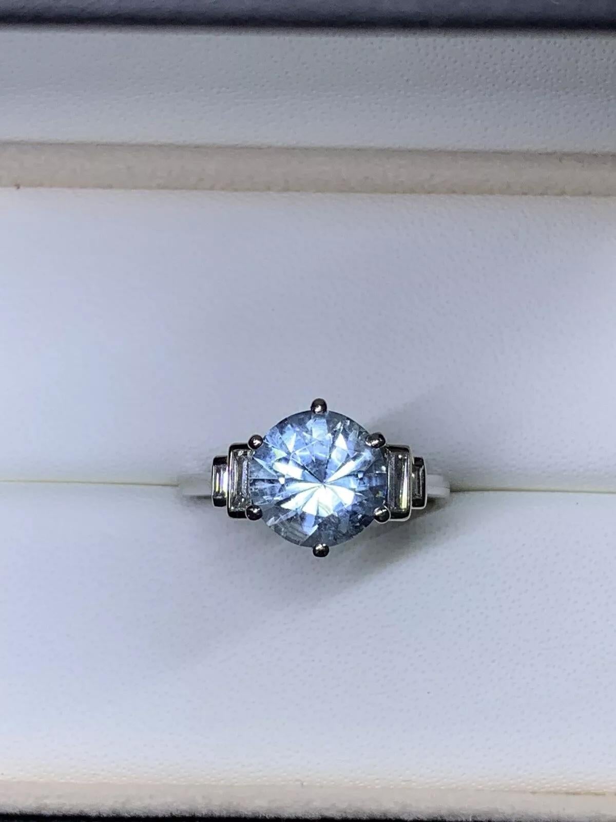 Anello di fidanzamento con acquamarina e smeraldo a gradini da 5,41 carati in platino.

Gemma rotonda Nature di acquamarina, peso totale 5,00ct

Testa in platino e fascia in oro bianco 18 ct.

Grande acquamarina di forma rotonda di colore blu vivido