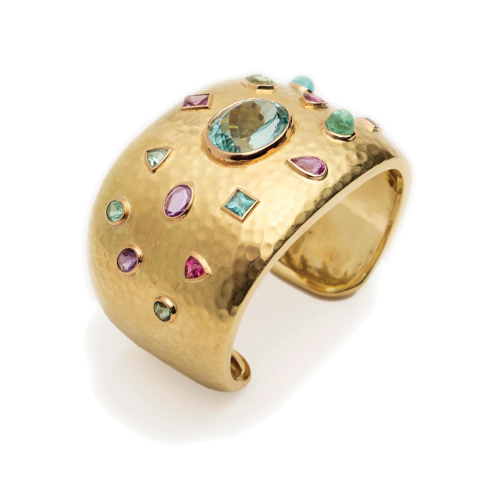 Fabulous, Bold and Brilliant! A magnificent Natural Blue/Green Aquamarine (21.9 Carat) is the centerpiece of this Hammered 18 Karat Gold Cuff, surrounded by exquisite Paraiba Tourmaline, Pink and Purple Sapphires and Pink and Green Tourmaline.

The