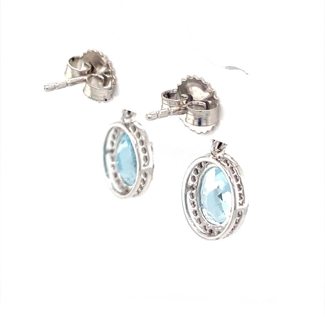 Earrings set in 18 carat white gold with a 0.40-carat diamond surrounding a 2.48-carat oval-shaped natural aquamarine and a 1.25-carat round sapphire. 
 