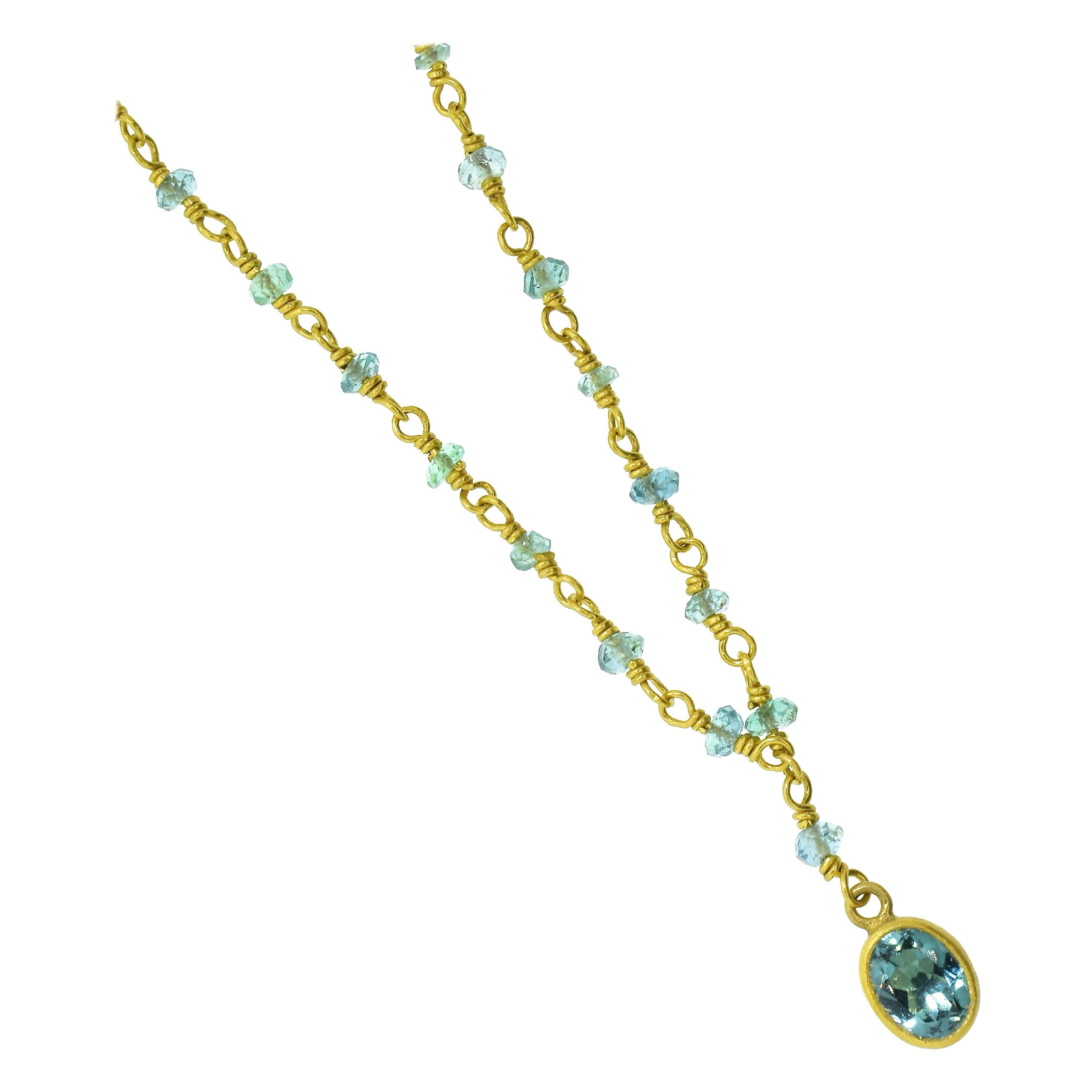 Aquamarine bezel set in 22K gold is suspended on a matching green/blue aquamarine and 14K yellow gold necklace which is 16.5 inches in length.  Contemporary in design, there are 66 natural aquamarine faceted beads interspersed in the gold chain. 